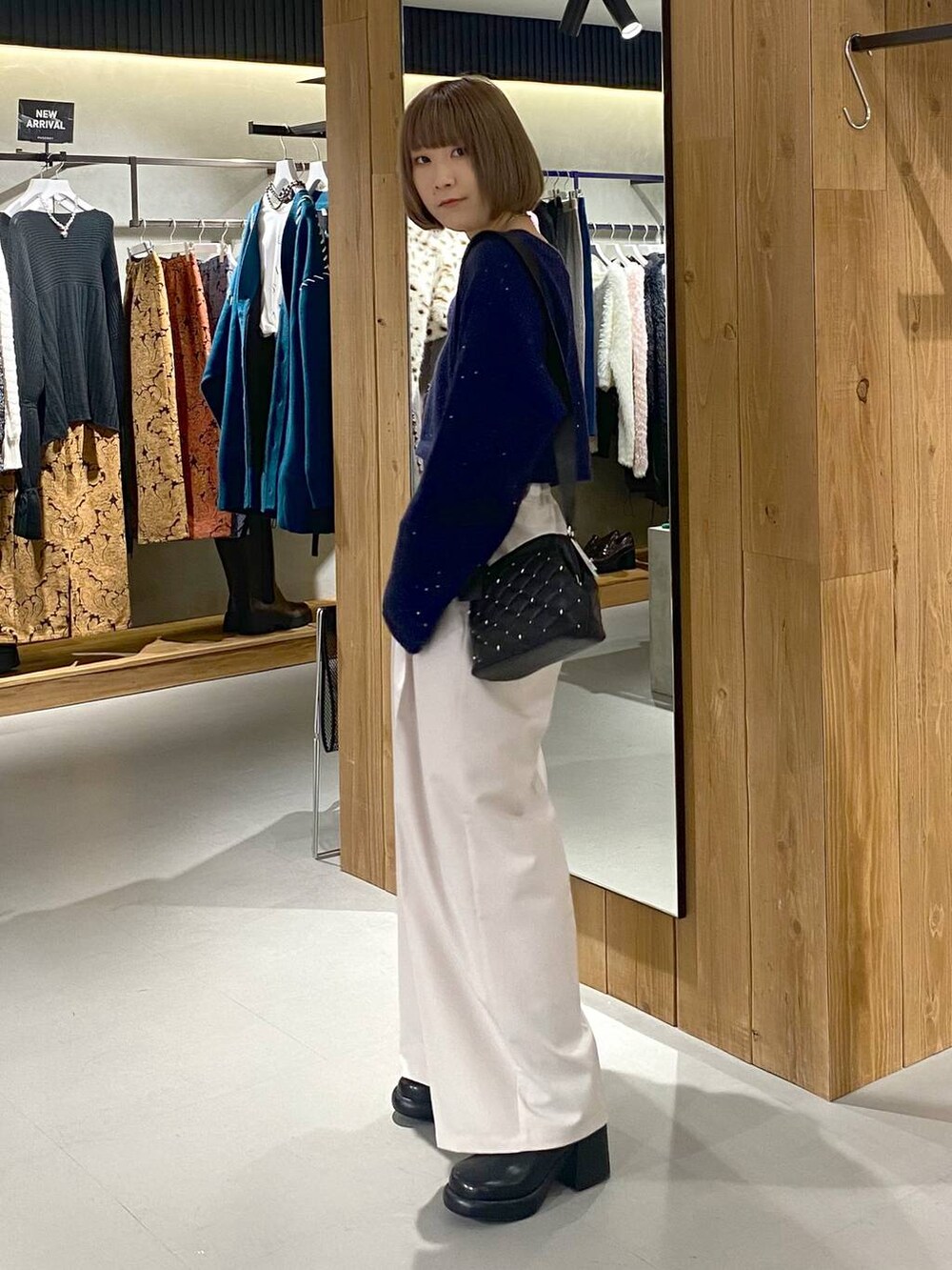 ホワイト系のキャミソール、ブラック系のブーツ、ベージュ系のスラックスを着用したレディースの冬コーディネートの5枚目の写真