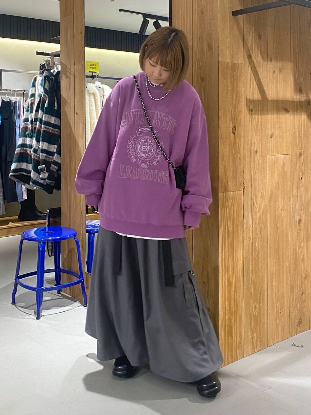 パープル系のスウェット、グレー系のジャンパースカート、ブラック系のブーツを着用したレディースの冬コーディネートの5枚目の写真