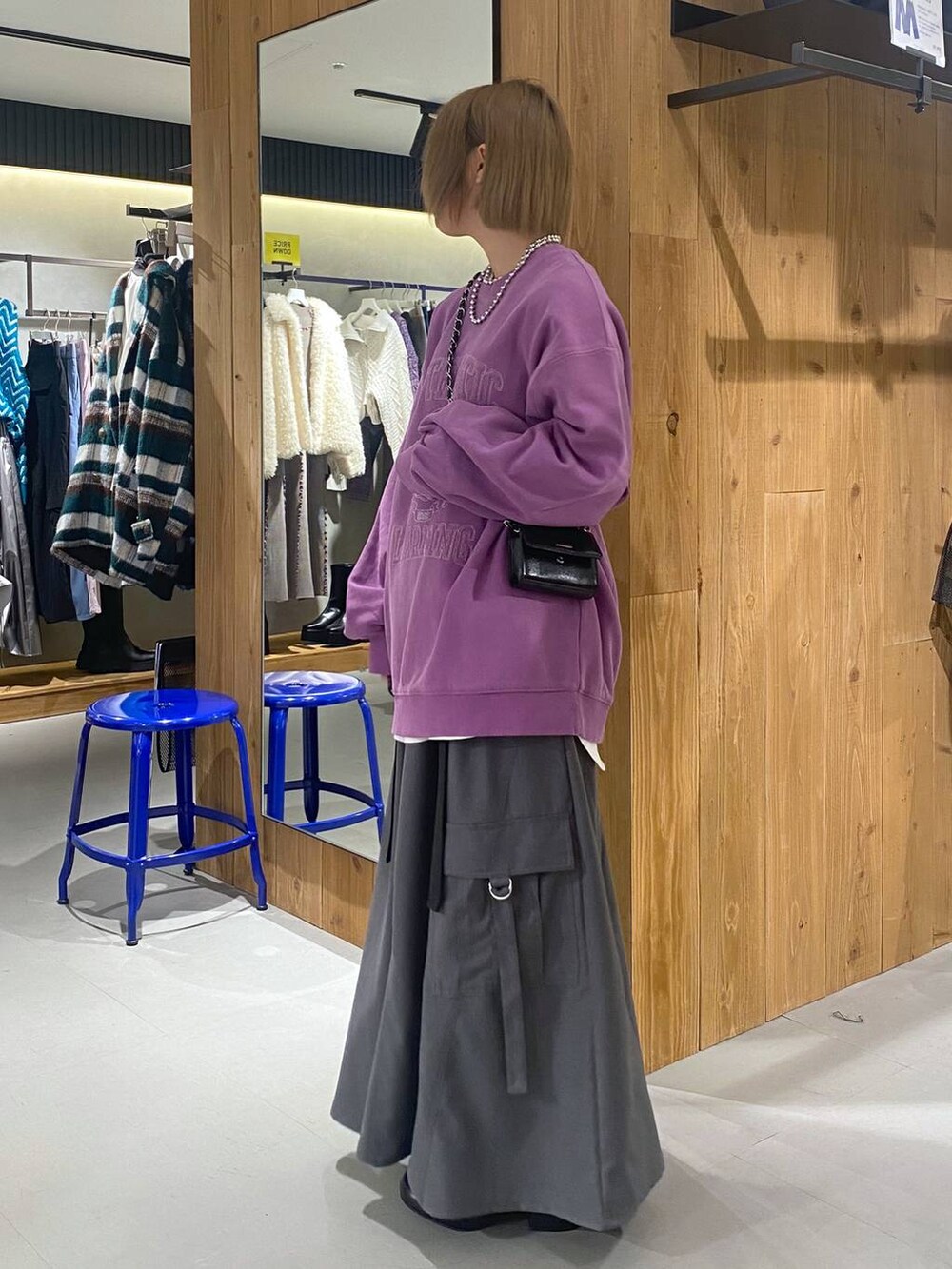 パープル系のスウェット、グレー系のジャンパースカート、ブラック系のブーツを着用したレディースの冬コーディネートの4枚目の写真