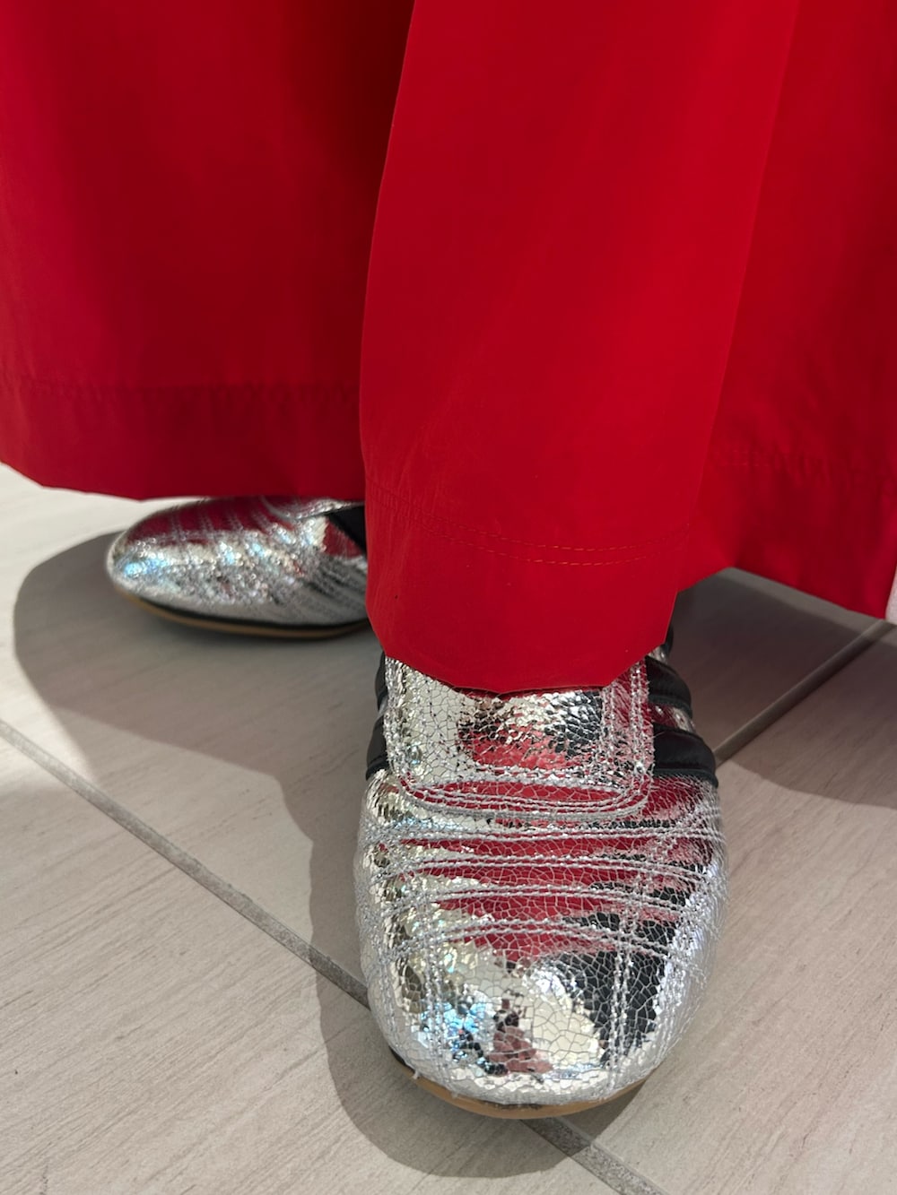 レッド系のパンツ、シルバー系のシューズを着用したレディースの冬コーディネートの2枚目の写真