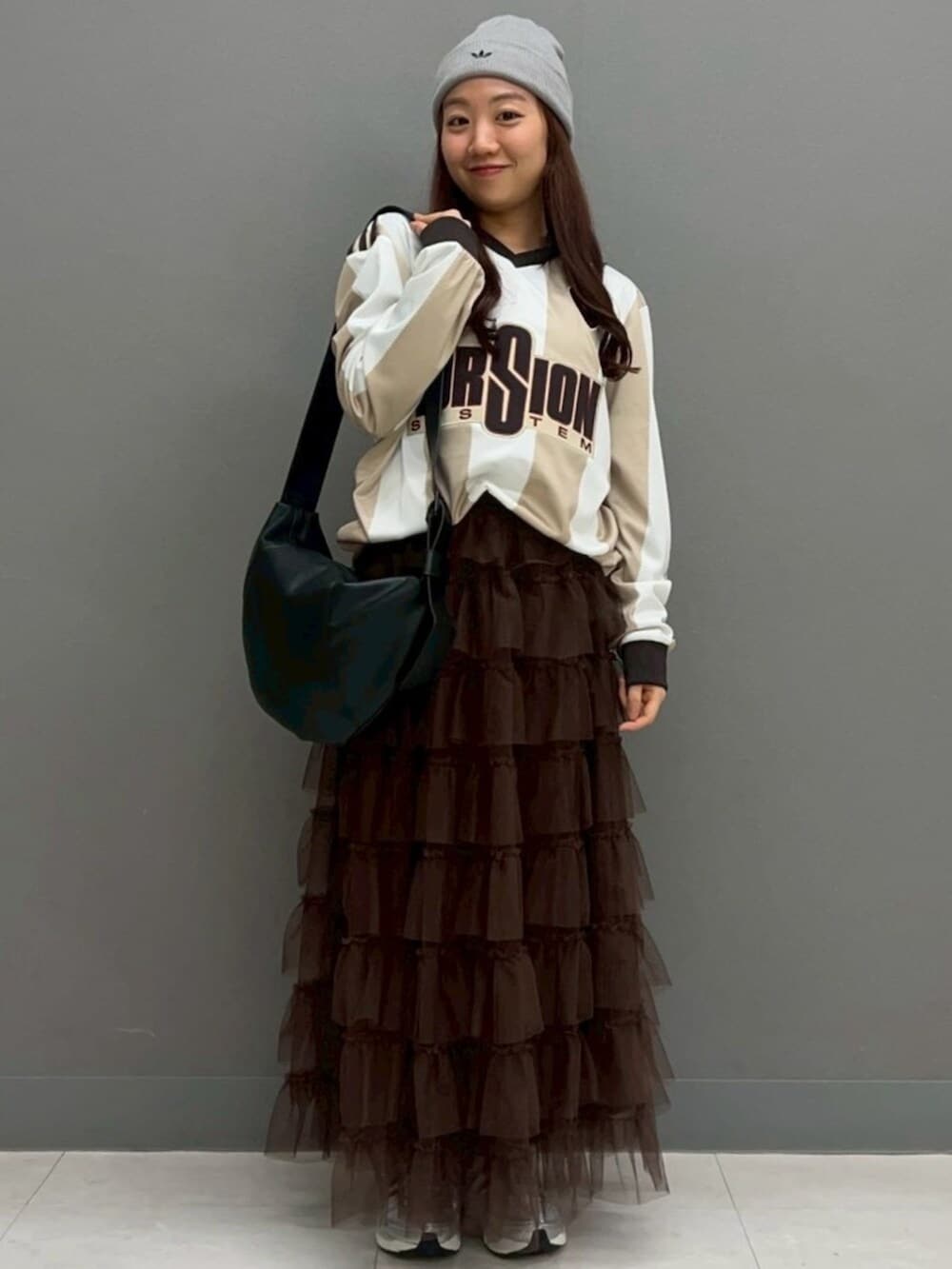 ホワイト系のトップス、シルバー系のスニーカー、ブラック系のショルダーバッグを着用したレディースの冬コーディネートの2枚目の写真