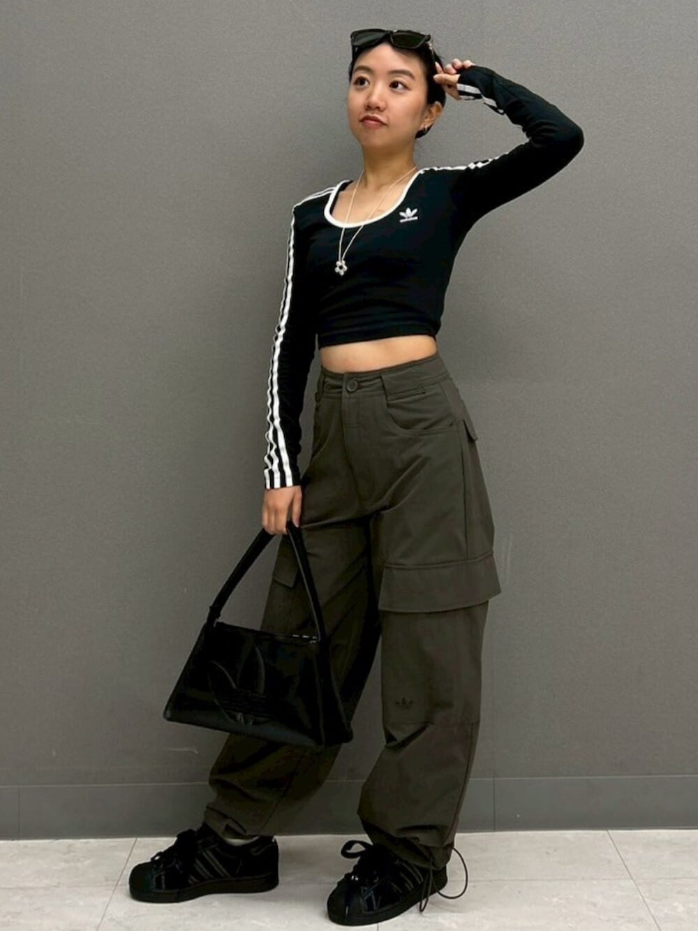 ブラック系のTシャツ/カットソー、グリーン系のカーゴパンツ、ブラック系のスニーカーを着用したレディースの春コーディネートの3枚目の写真