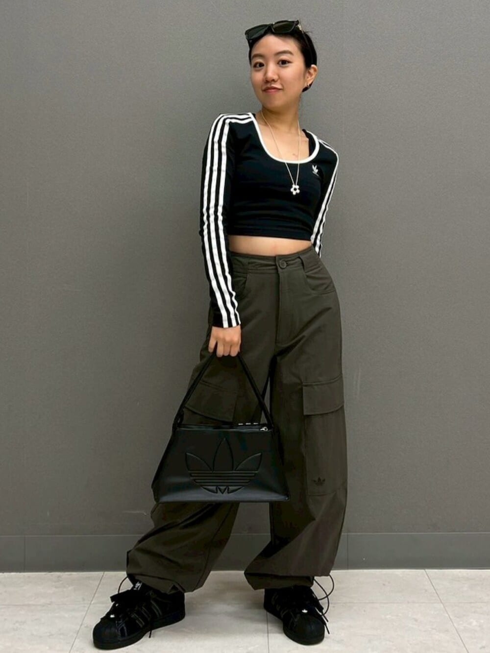 ブラック系のTシャツ/カットソー、グリーン系のカーゴパンツ、ブラック系のスニーカーを着用したレディースの春コーディネートの2枚目の写真