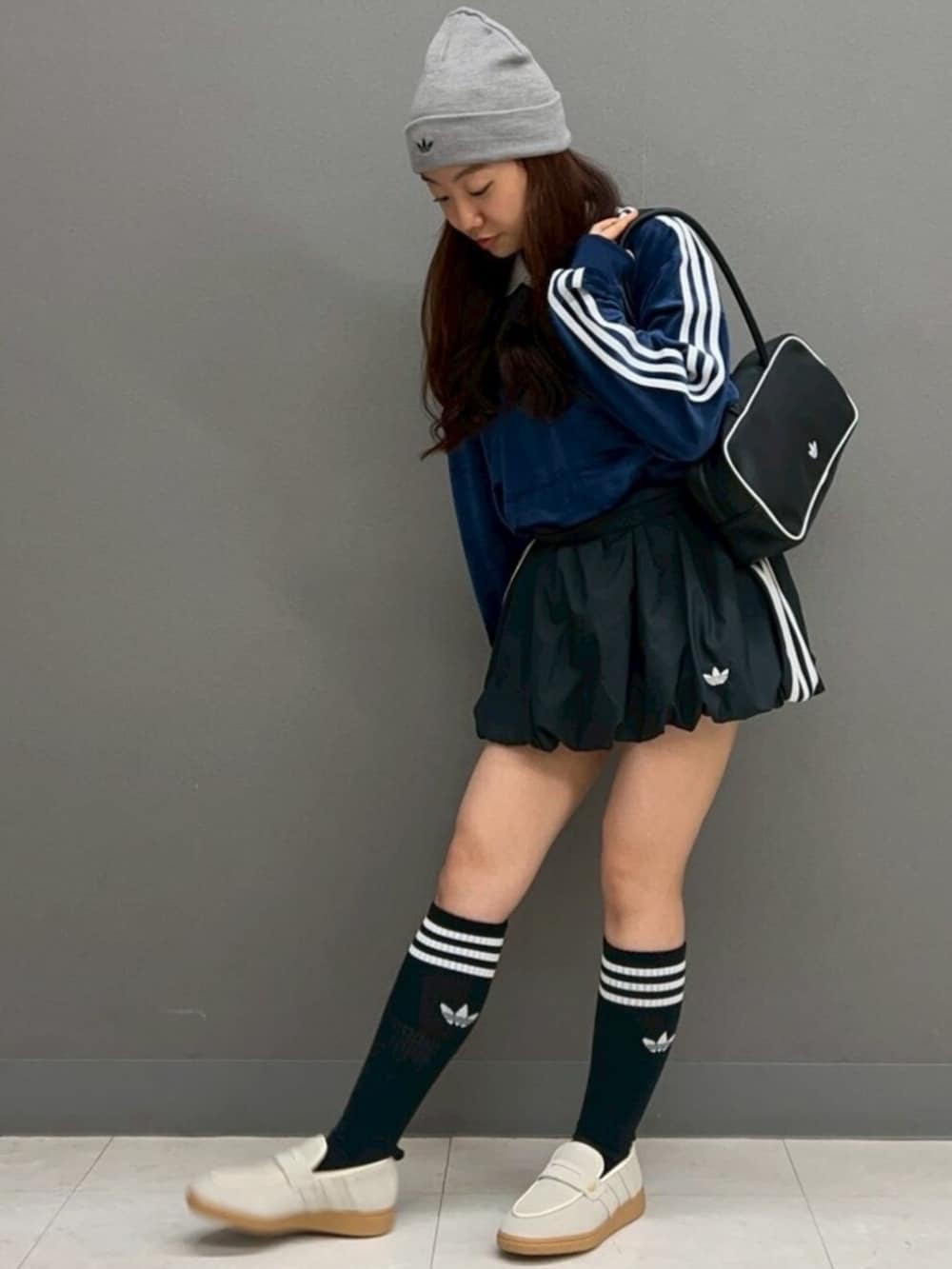 ブラック系のスカート、ブラック系のショルダーバッグ、ブルー系のポロシャツを着用したレディースの冬コーディネートの3枚目の写真