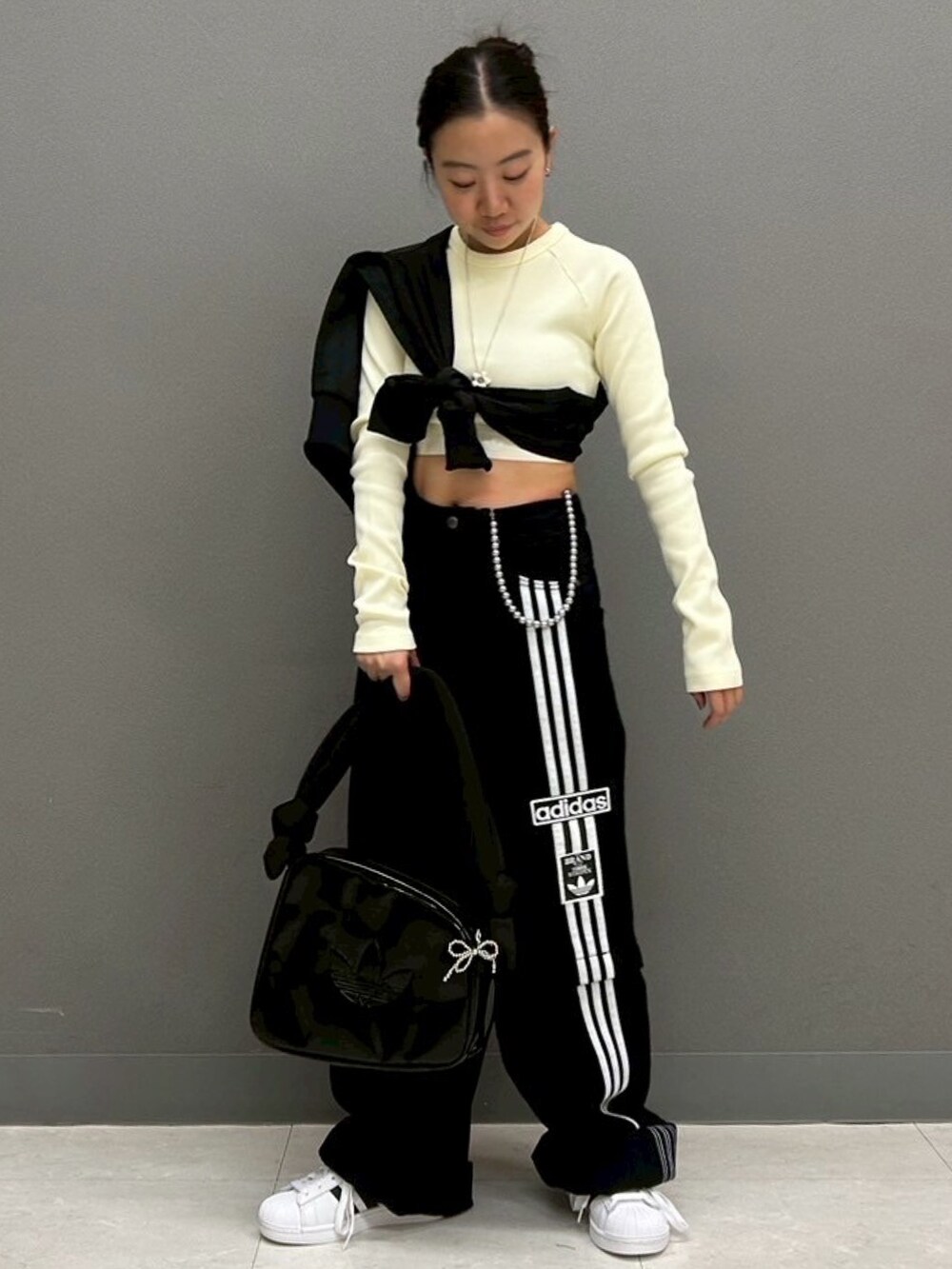 ホワイト系のトップス、ブラック系のデニムパンツ、ホワイト系のスニーカーを着用したレディースの春コーディネートの2枚目の写真