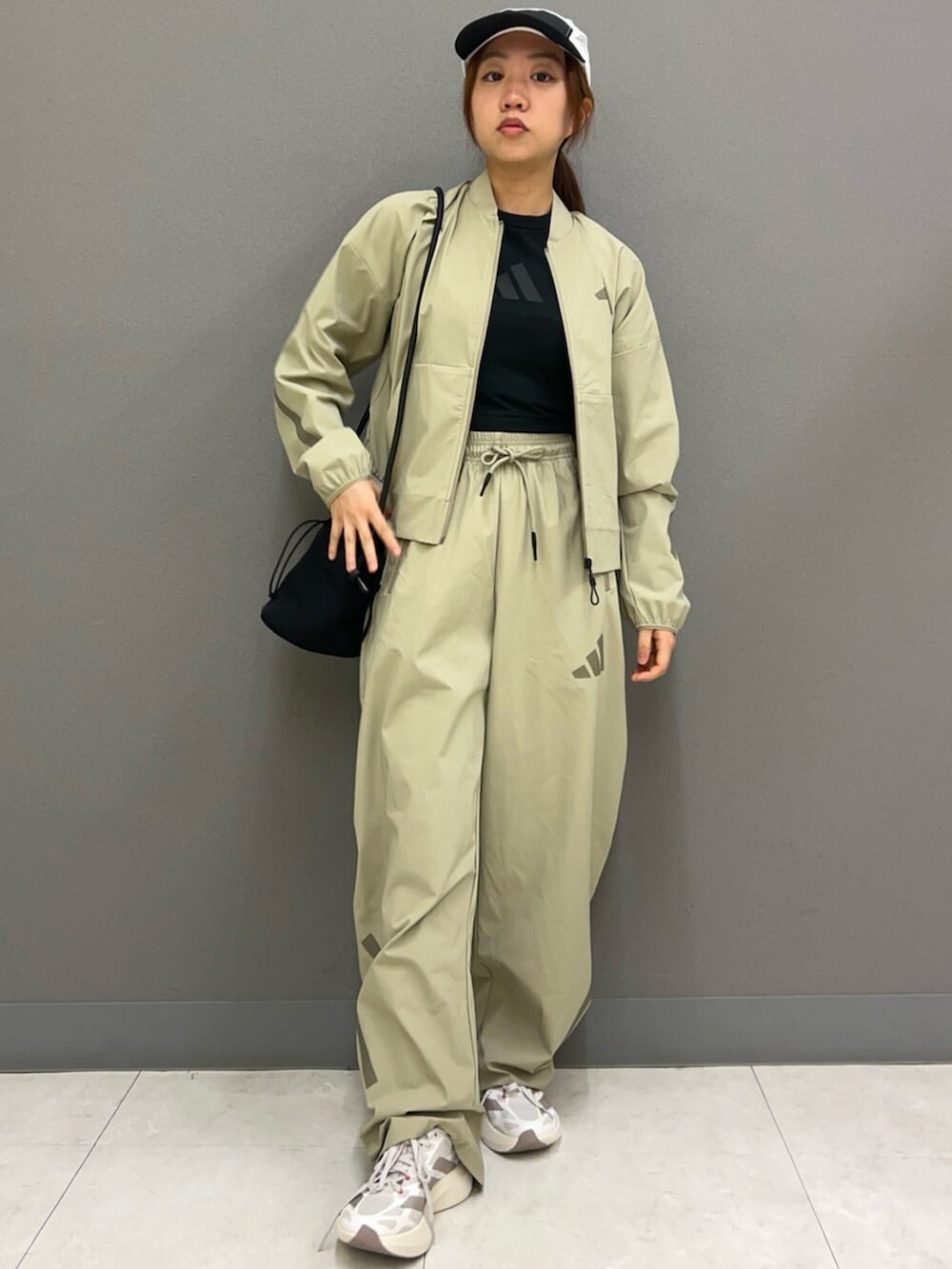 ベージュ系のMA-1、ブラック系のタンクトップ、グリーン系のスウェットパンツを着用したレディースの春コーディネートの3枚目の写真