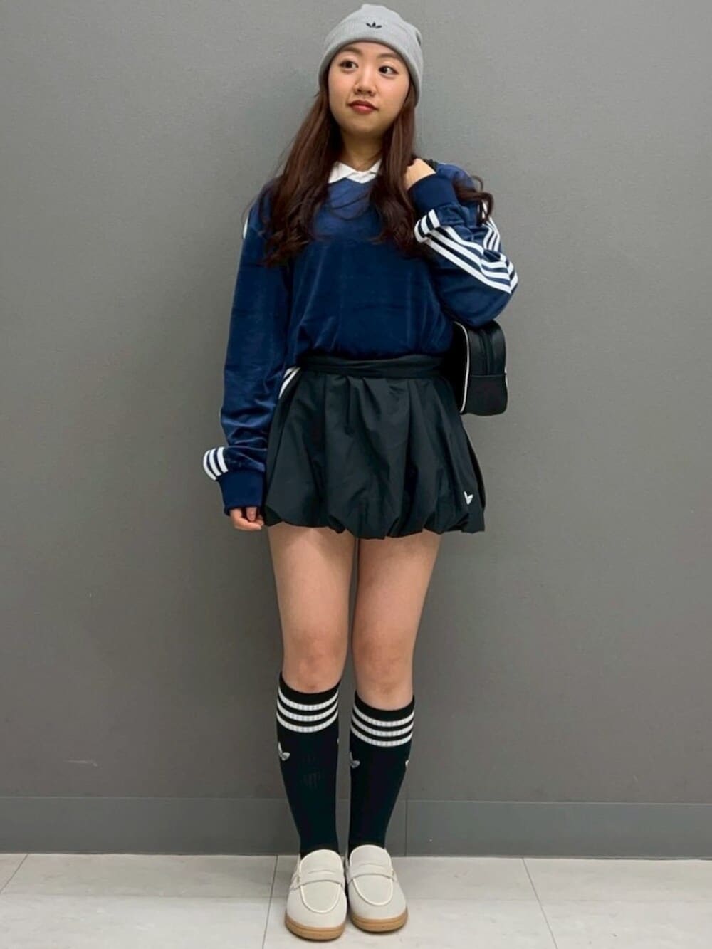 ブラック系のスカート、ブラック系のショルダーバッグ、ブルー系のポロシャツを着用したレディースの冬コーディネートの2枚目の写真