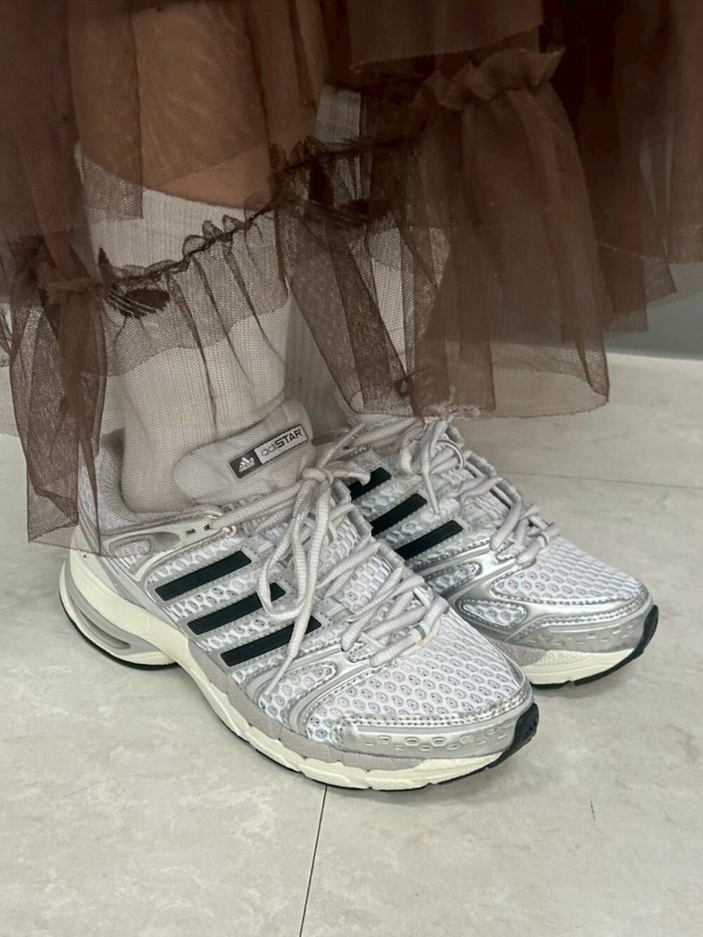 ホワイト系のトップス、シルバー系のスニーカー、ブラック系のショルダーバッグを着用したレディースの冬コーディネートの4枚目の写真