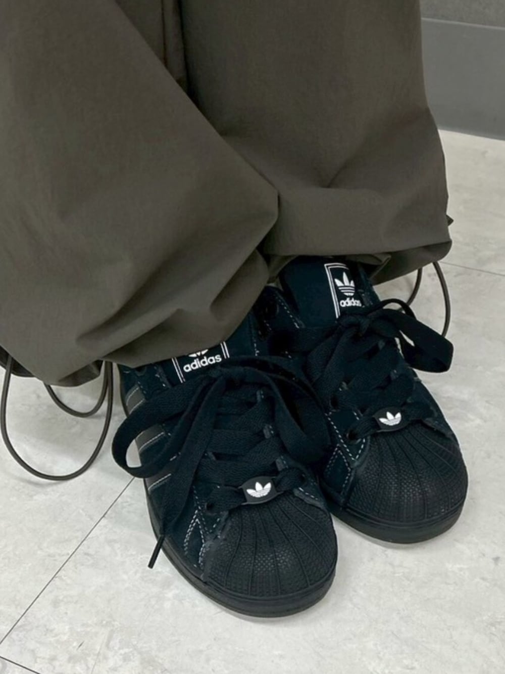 ブラック系のTシャツ/カットソー、グリーン系のカーゴパンツ、ブラック系のスニーカーを着用したレディースの春コーディネートの4枚目の写真