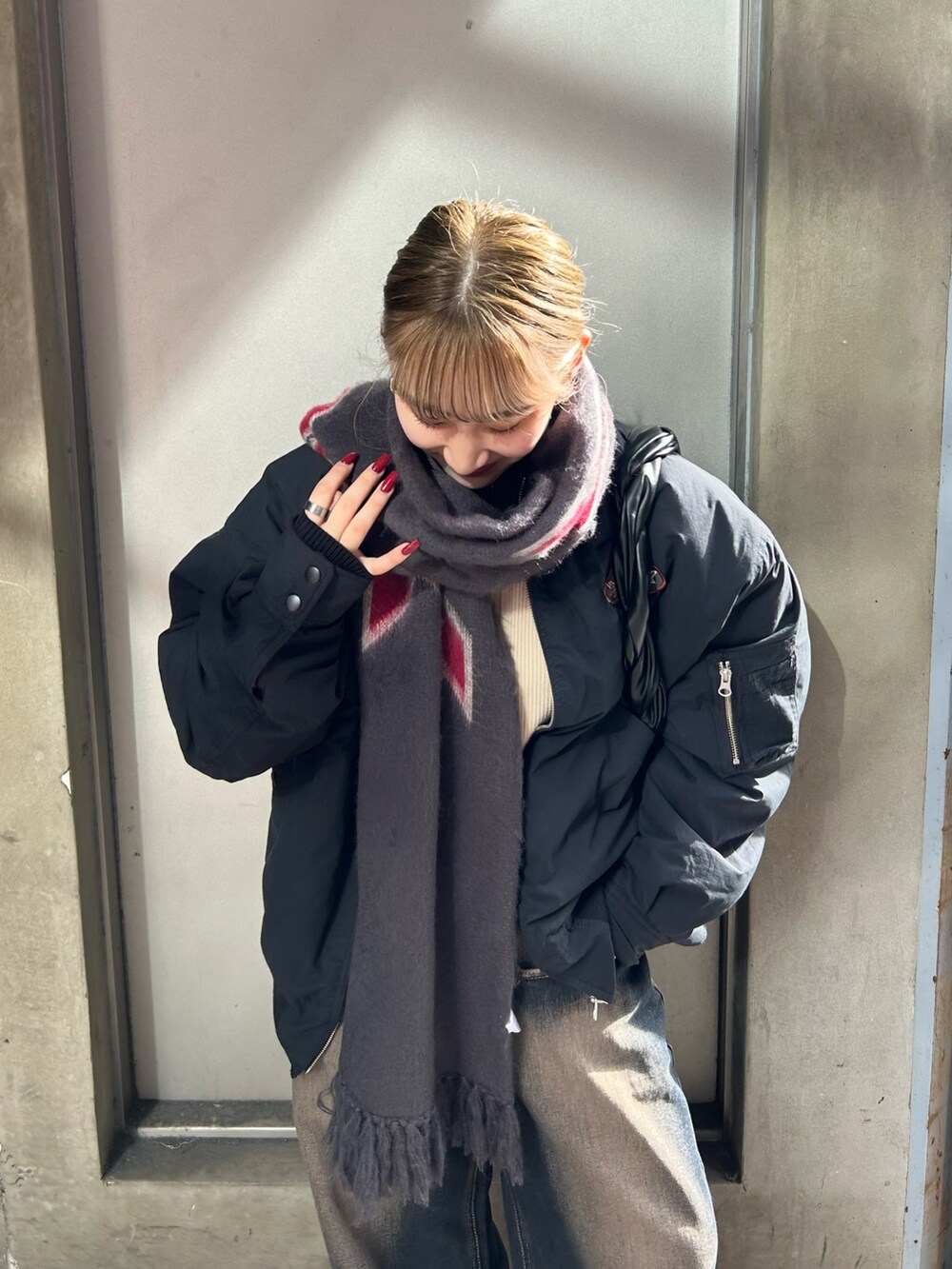 ブルー系のデニムパンツ、ブラック系のブルゾン、ブラック系のマフラーを着用したレディースの冬コーディネートの3枚目の写真