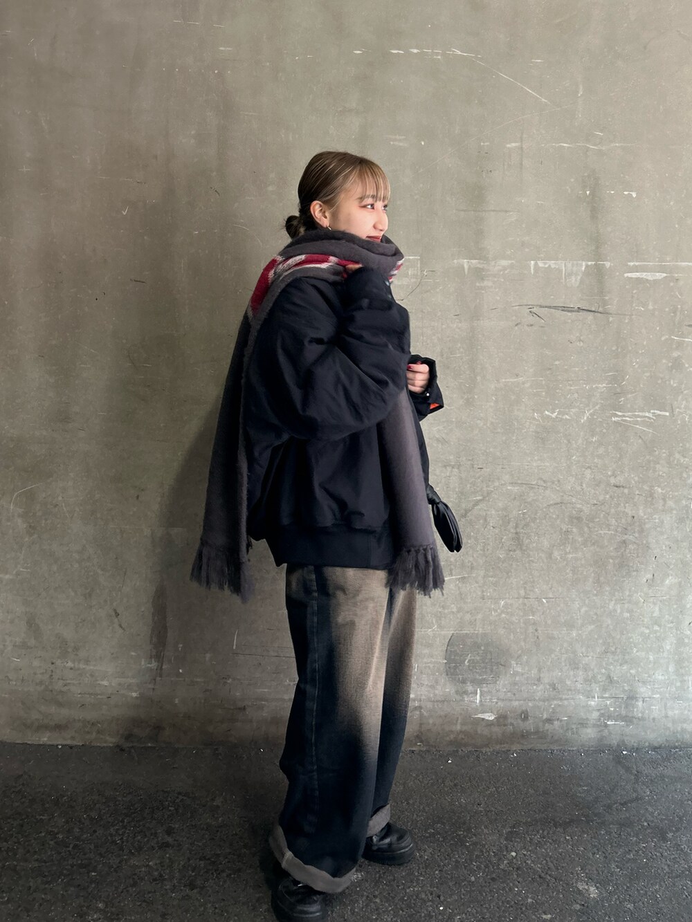 ブルー系のデニムパンツ、ブラック系のブルゾン、ブラック系のマフラーを着用したレディースの冬コーディネートの2枚目の写真