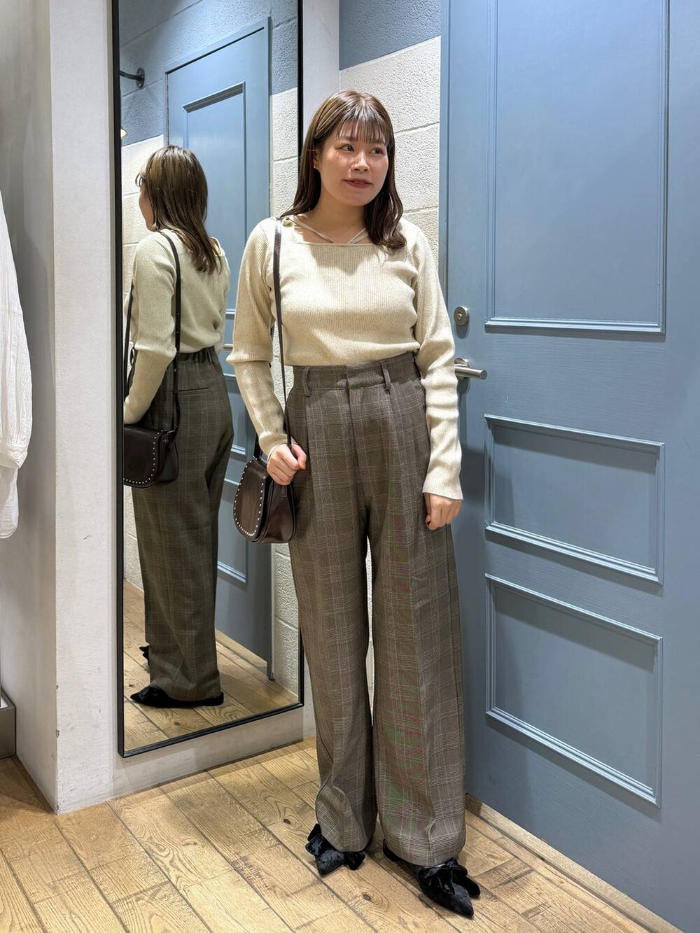 ブラック系のパンプス、ブラウン系のショルダーバッグ、ブラウン系のスラックスを着用したレディースの秋コーディネートの4枚目の写真