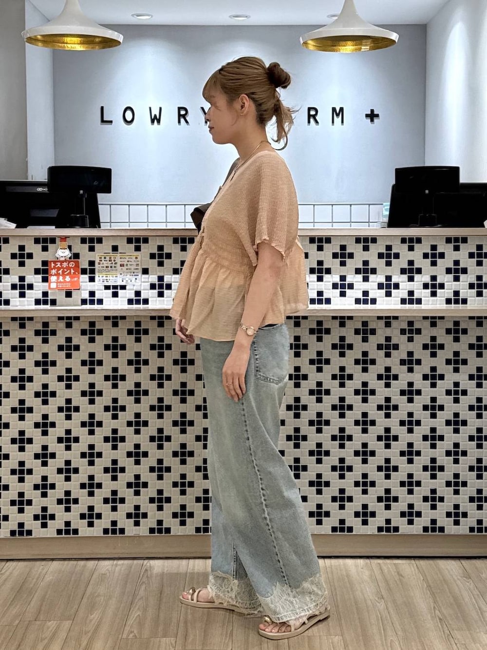 ブルー系のデニムパンツ、ホワイト系のサンダル、ホワイト系のショルダーバッグを着用したレディースの夏コーディネートの3枚目の写真