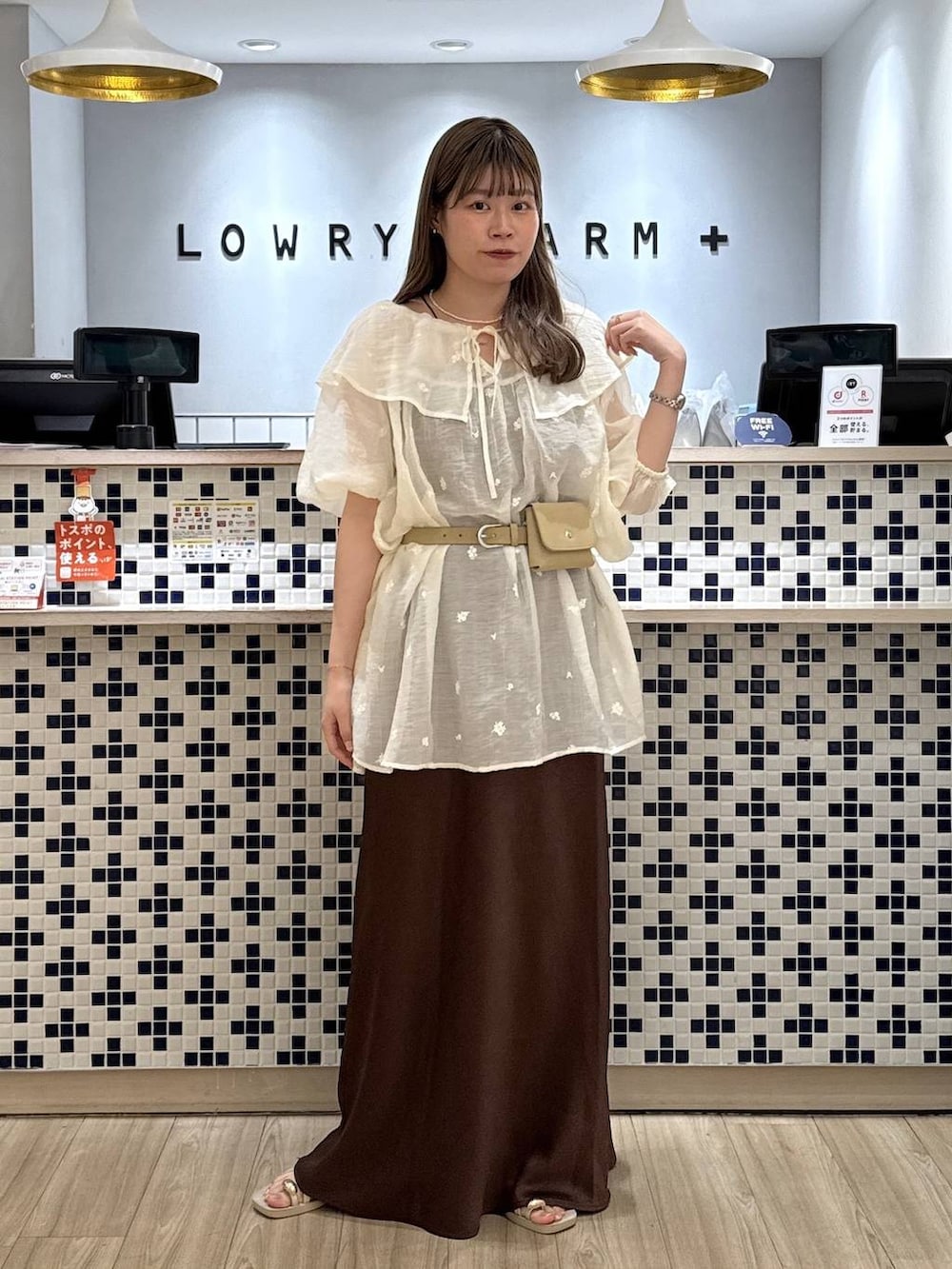 ホワイト系のワンピース、ブラウン系のスカート、ホワイト系のサンダルを着用したレディースの夏コーディネートの2枚目の写真