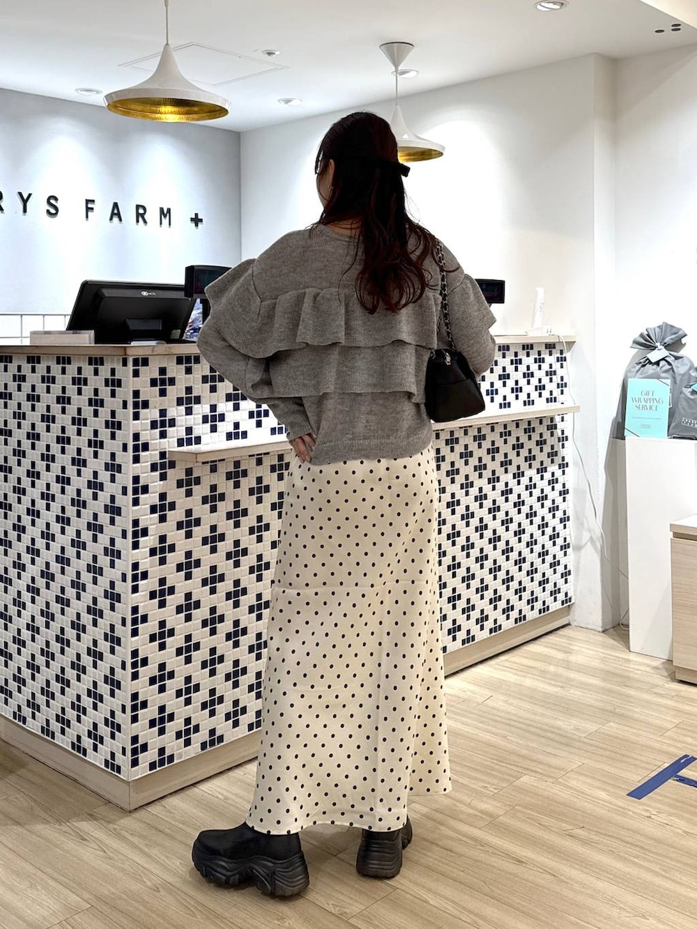 ブラック系のブーツ、ホワイト系のスカート、ブラック系のショルダーバッグを着用したレディースの冬コーディネートの5枚目の写真