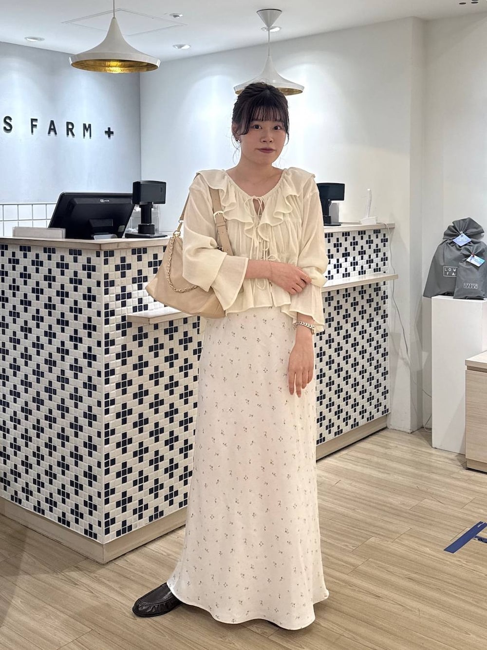 ホワイト系のスカート、ベージュ系のショルダーバッグ、ブラウン系のローファーを着用したレディースの春コーディネートの4枚目の写真