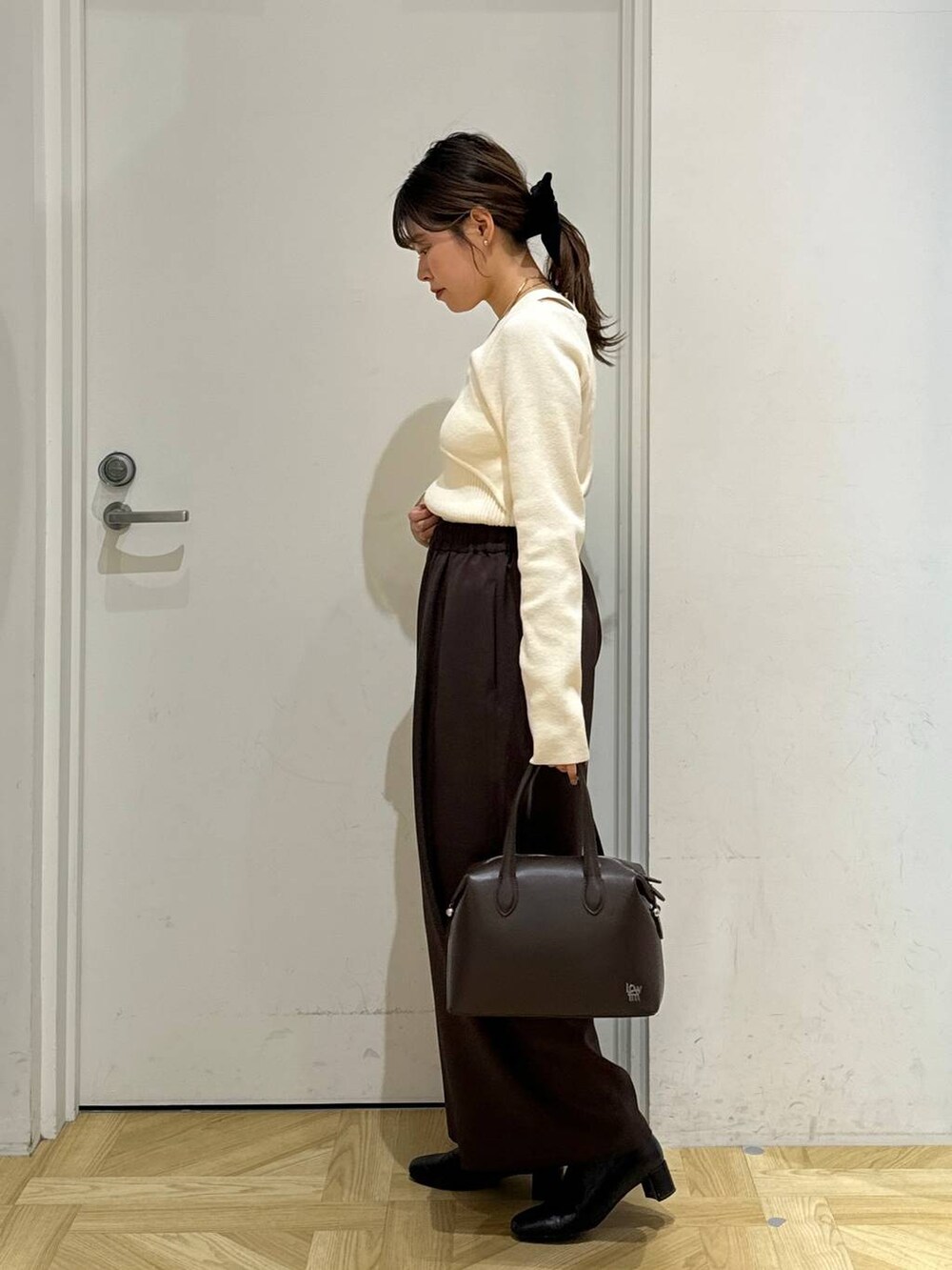 ブラック系のブーツ、ブラウン系のショルダーバッグ、ホワイト系のブルゾンを着用したレディースの冬コーディネートの7枚目の写真