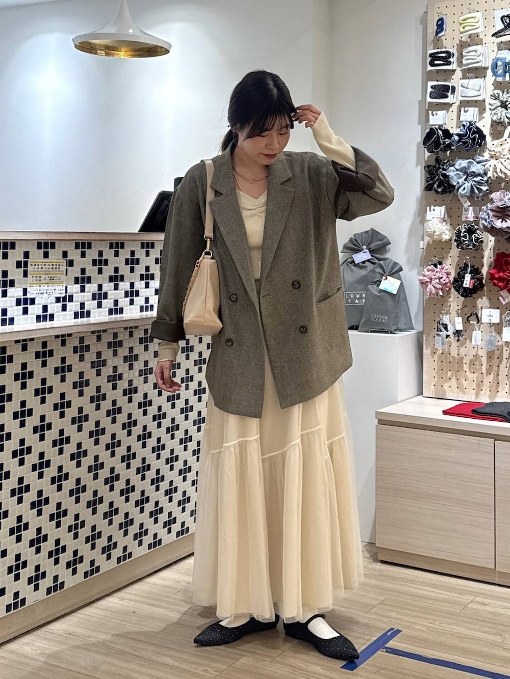 ブラック系のパンプス、ブラウン系のテーラードジャケット、ベージュ系のショルダーバッグを着用したレディースの春コーディネートの3枚目の写真