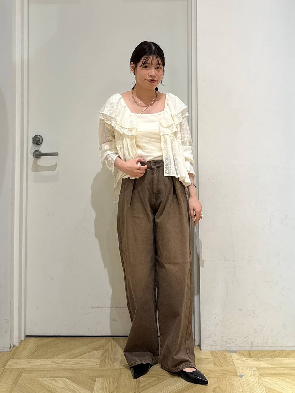 ブラウン系のデニムパンツ、ブラック系のパンプス、ホワイト系のシャツ/ブラウスを着用したレディースの夏コーディネートの2枚目の写真