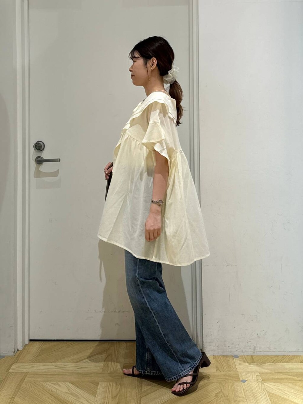 ブラウン系のショルダーバッグ、ブラック系のサンダル、ホワイト系のシャツ/ブラウスを着用したレディースの夏コーディネートの3枚目の写真