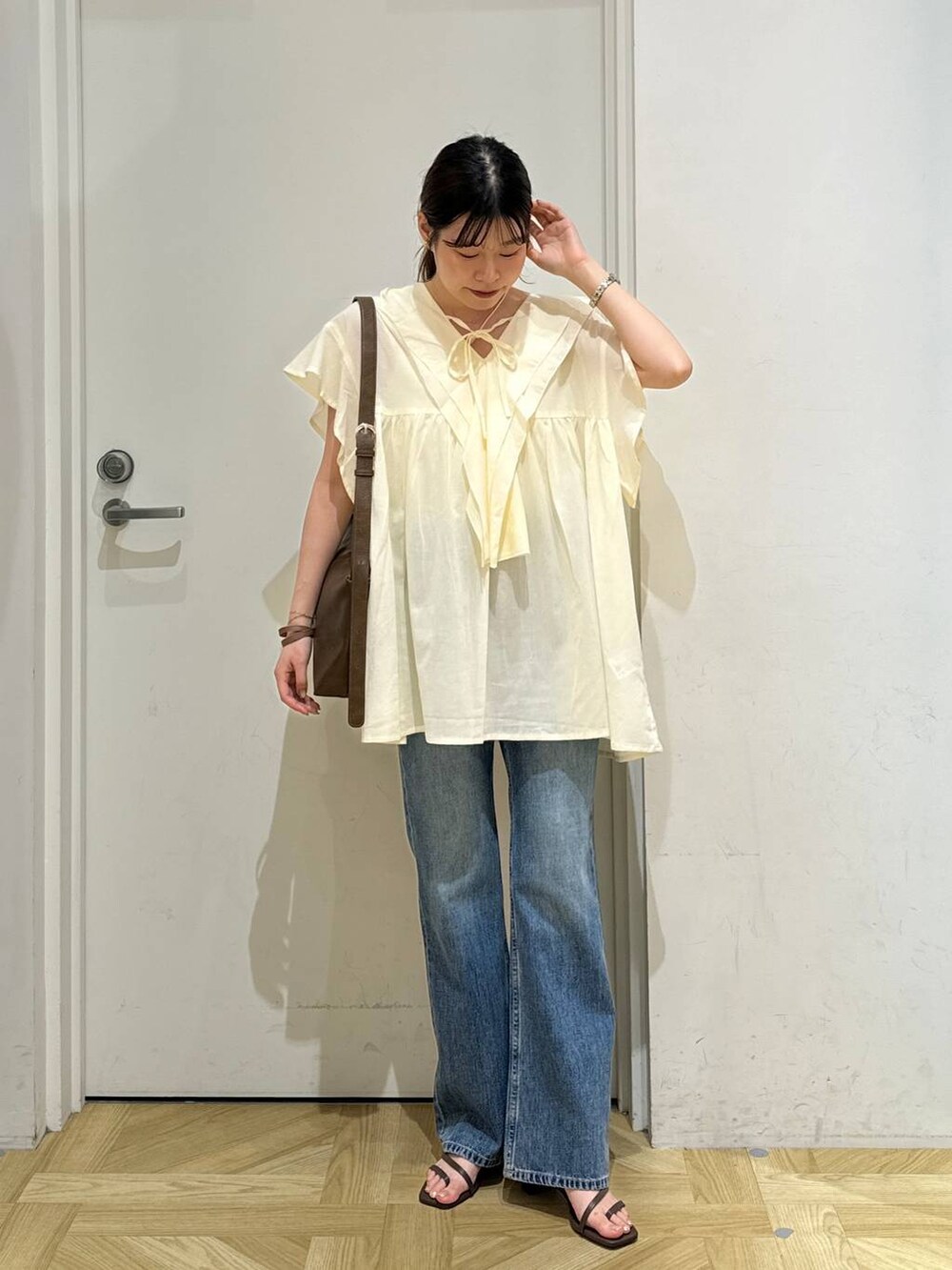 ブラウン系のショルダーバッグ、ブラック系のサンダル、ホワイト系のシャツ/ブラウスを着用したレディースの夏コーディネートの2枚目の写真