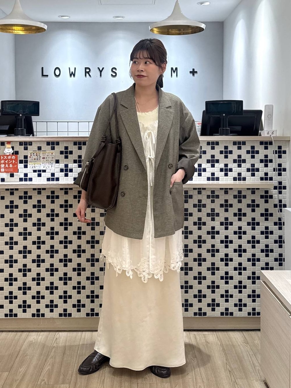 ホワイト系のスカート、ブラウン系のテーラードジャケット、ブラウン系のローファーを着用したレディースの春コーディネートの5枚目の写真