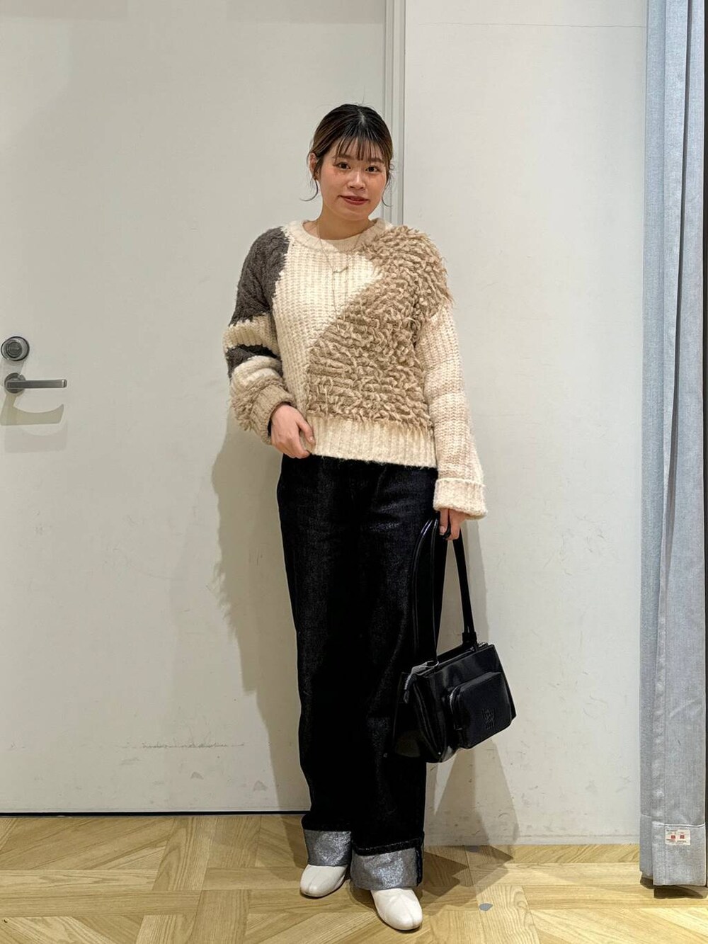 グレー系のデニムパンツ、ブラック系のショルダーバッグ、ホワイト系のブーツを着用したレディースの冬コーディネートの2枚目の写真