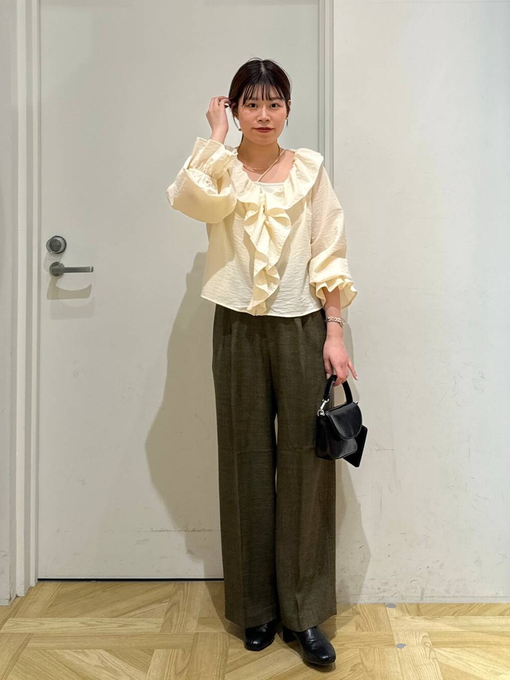 ブラック系のブーツ、ブラウン系のスラックス、ホワイト系のキャミソールを着用したレディースの春コーディネートの4枚目の写真