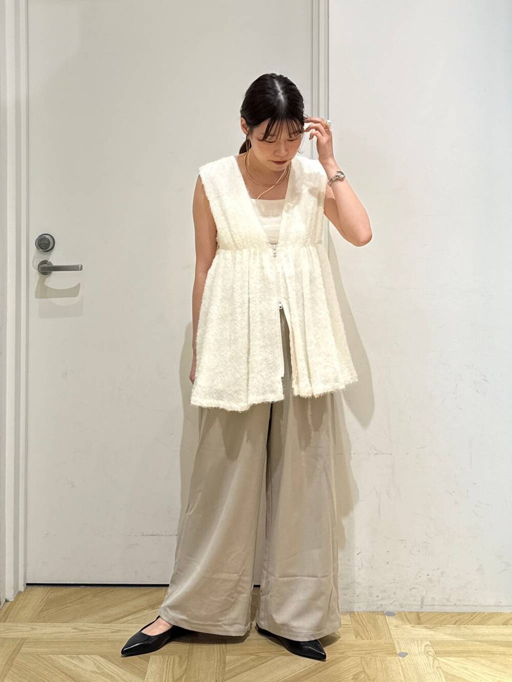 ベージュ系のその他パンツ、ブラック系のパンプス、ホワイト系のベストを着用したレディースの秋コーディネートの4枚目の写真