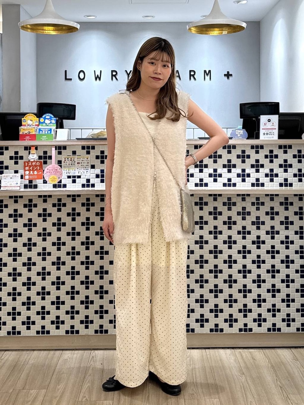 ゴールド系のショルダーバッグ、ホワイト系のベスト、ホワイト系のその他パンツを着用したレディースの秋コーディネートの2枚目の写真