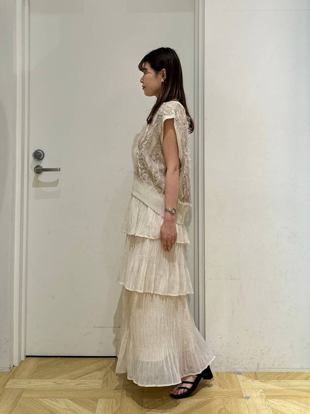 ブラック系のサンダル、ベージュ系のニット/セーター、ホワイト系のスカートを着用したレディースの夏コーディネートの3枚目の写真