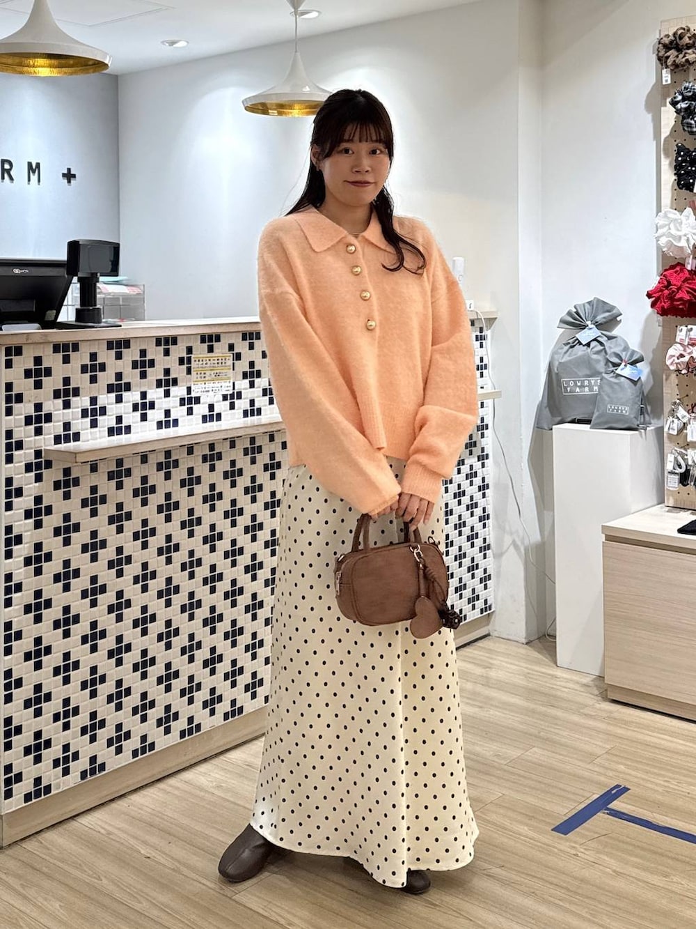 ホワイト系のスカート、ブラウン系のボストンバッグ、ブラウン系のブーツを着用したレディースの冬コーディネートの2枚目の写真