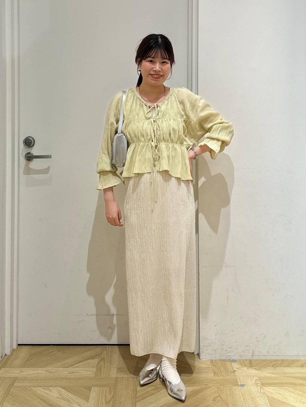 シルバー系のトートバッグ、シルバー系のパンプス、ホワイト系のスカートを着用したレディースの春コーディネートの2枚目の写真