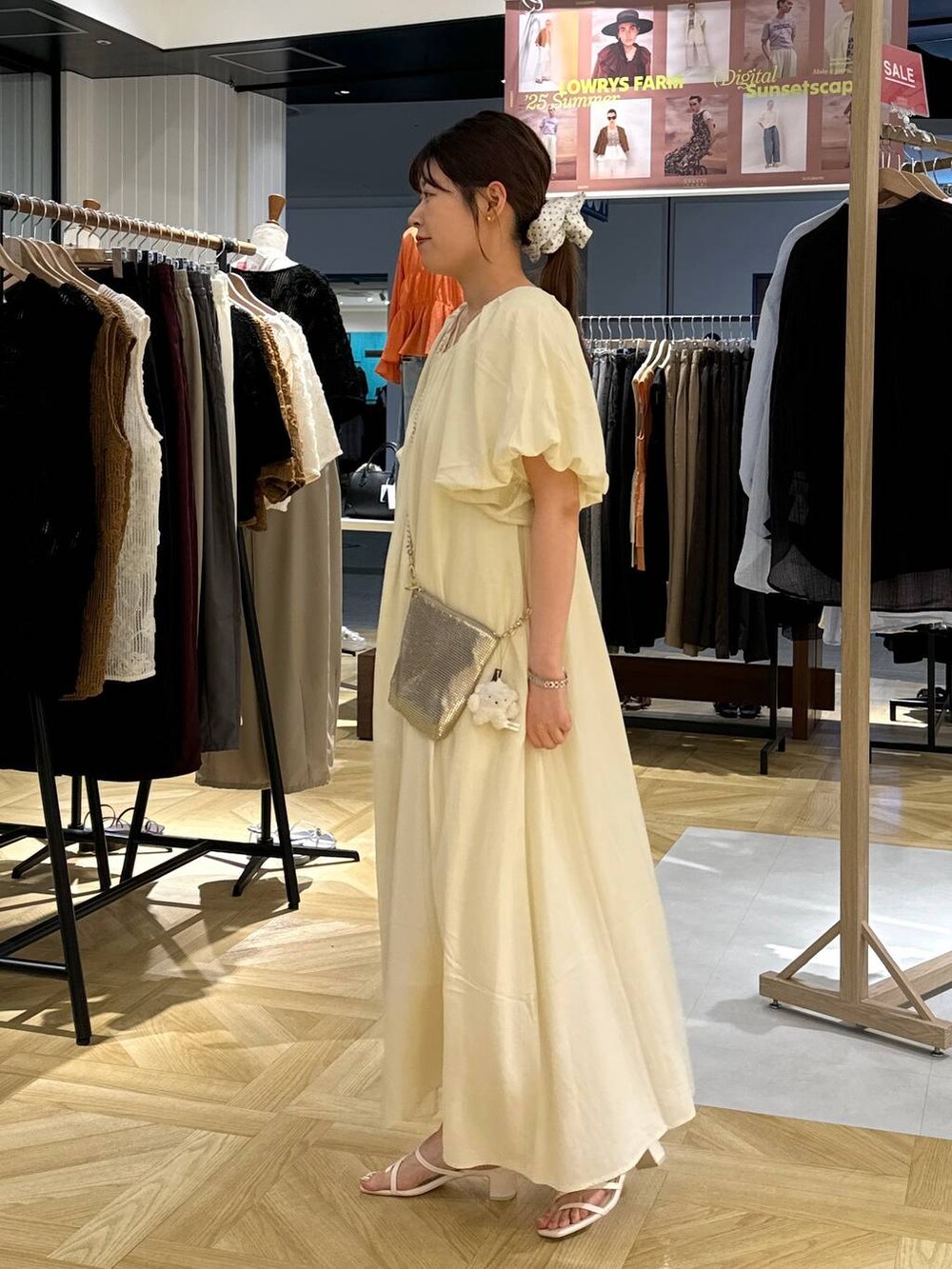 ゴールド系のショルダーバッグ、ホワイト系のサンダル、ホワイト系のワンピースを着用したレディースの夏コーディネートの3枚目の写真