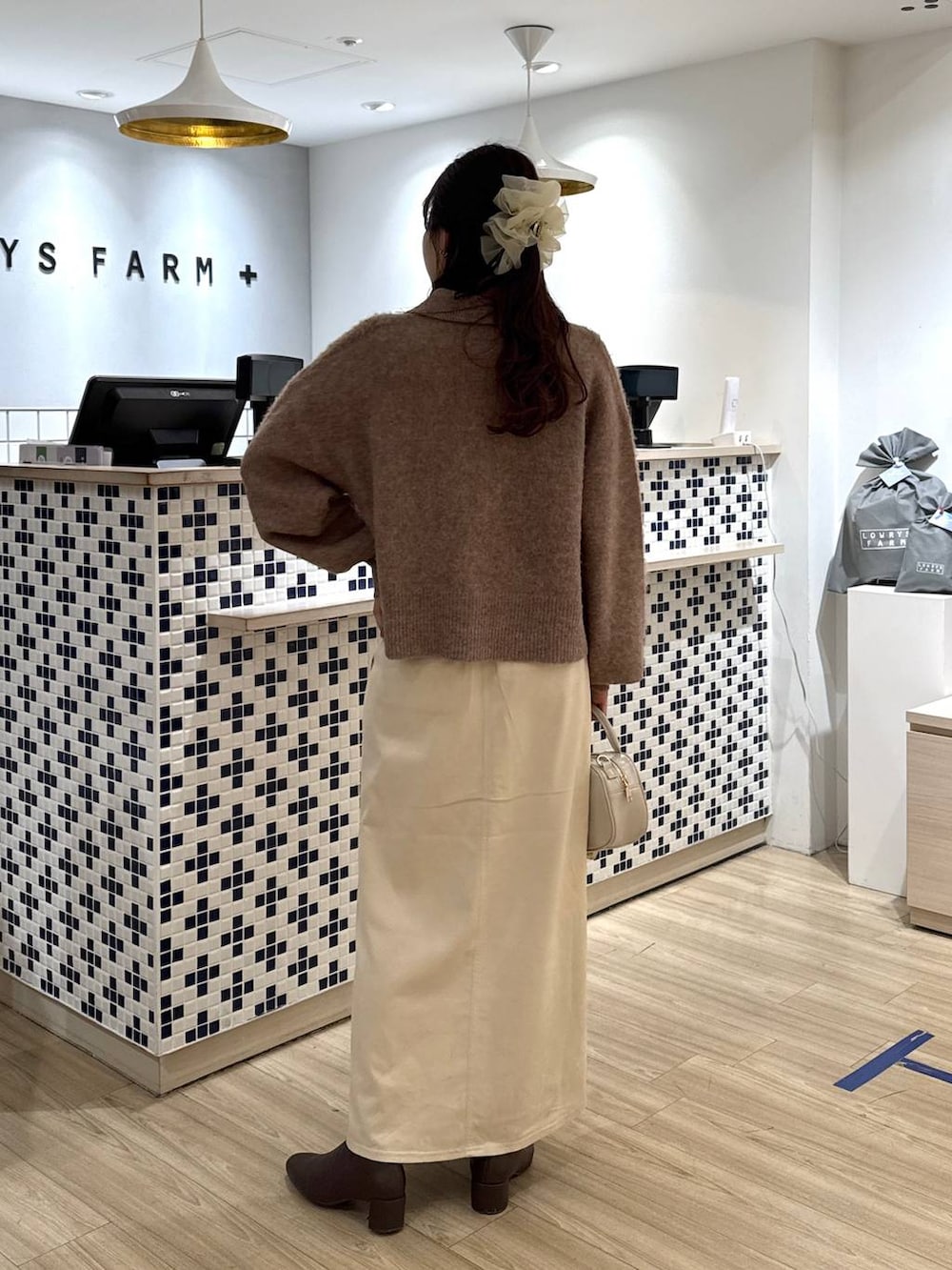 ホワイト系のスカート、ホワイト系のボストンバッグ、ブラウン系のブーツを着用したレディースの冬コーディネートの4枚目の写真