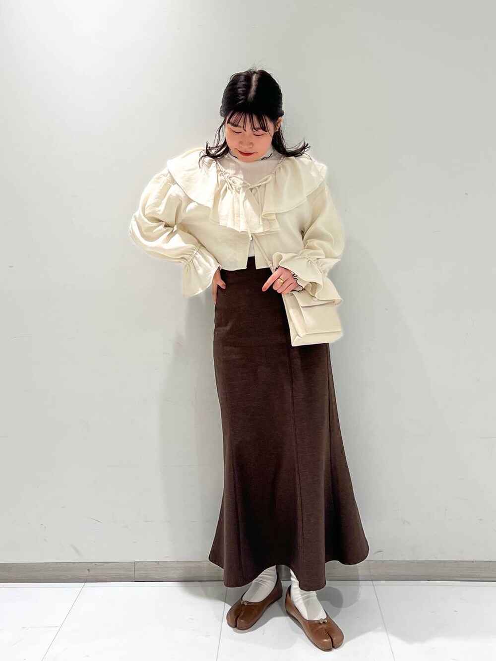 ホワイト系のショルダーバッグ、その他のTシャツ/カットソー、ブラウン系のスカートを着用したレディースの冬コーディネートの3枚目の写真