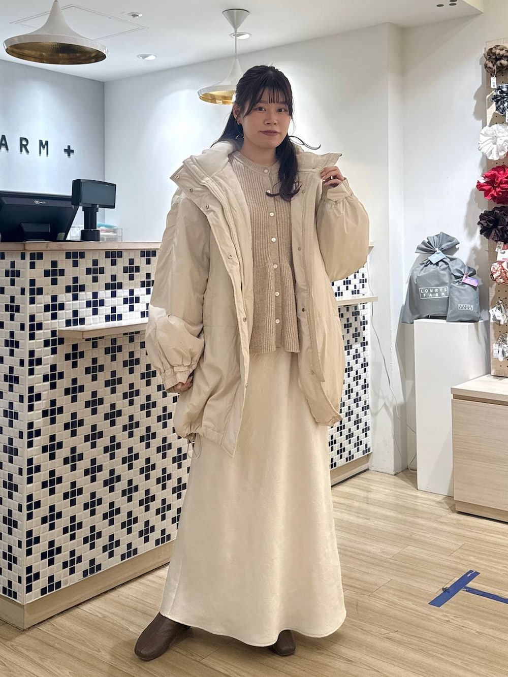 ホワイト系のスカート、ベージュ系のカーディガン/ボレロ、ブラウン系のブーツを着用したレディースの冬コーディネートの2枚目の写真