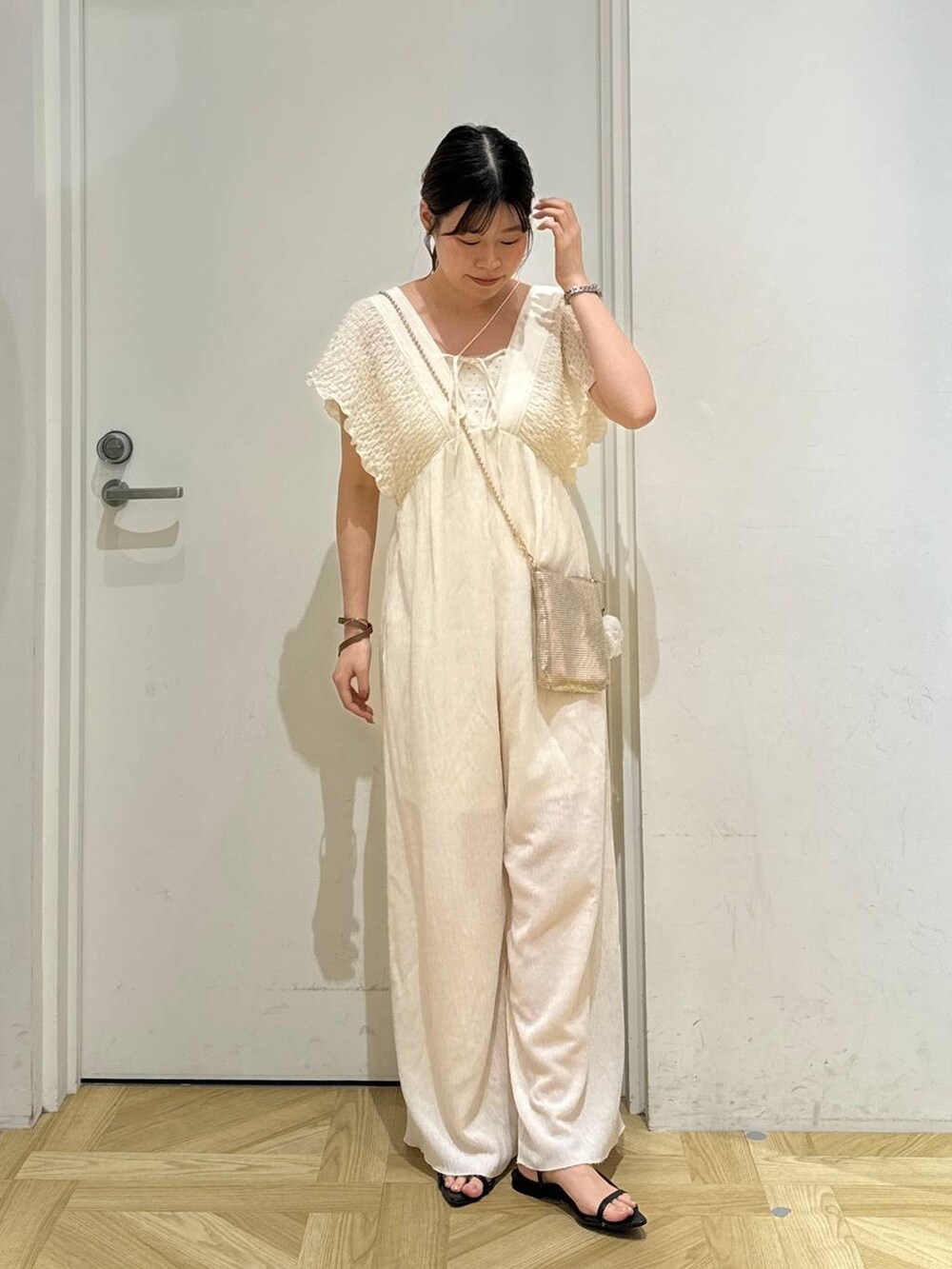 ゴールド系のショルダーバッグ、ブラック系のサンダル、ホワイト系のサロペット/オーバーオールを着用したレディースの夏コーディネートの3枚目の写真