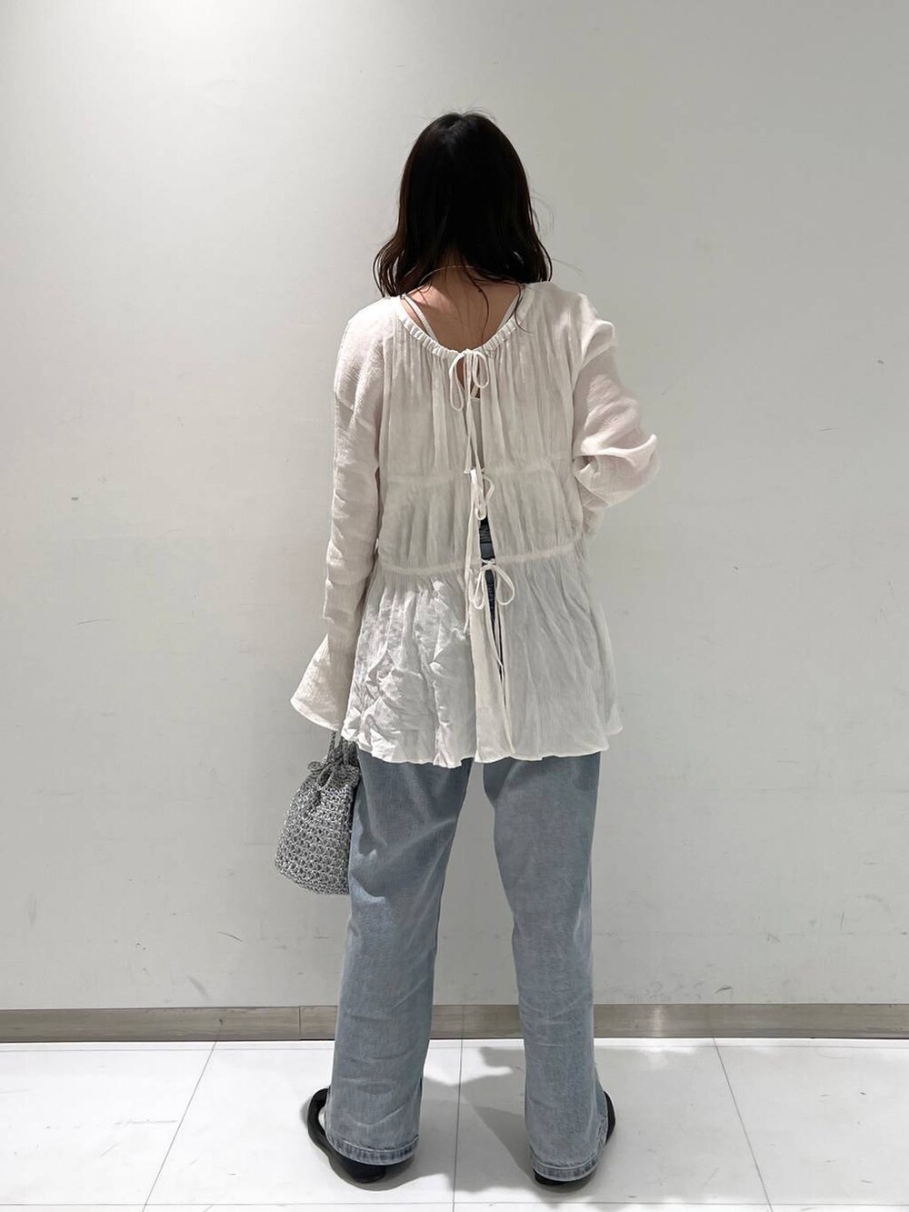 ホワイト系のシャツ/ブラウス、ブラック系のバレエシューズ、ブルー系のデニムパンツを着用したレディースの春コーディネートの4枚目の写真