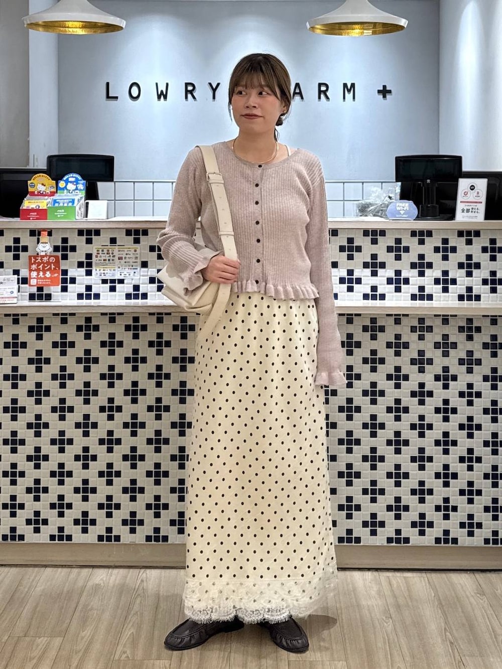 ホワイト系のショルダーバッグ、ピンク系のカーディガン/ボレロ、ブラウン系のローファーを着用したレディースの秋コーディネートの2枚目の写真