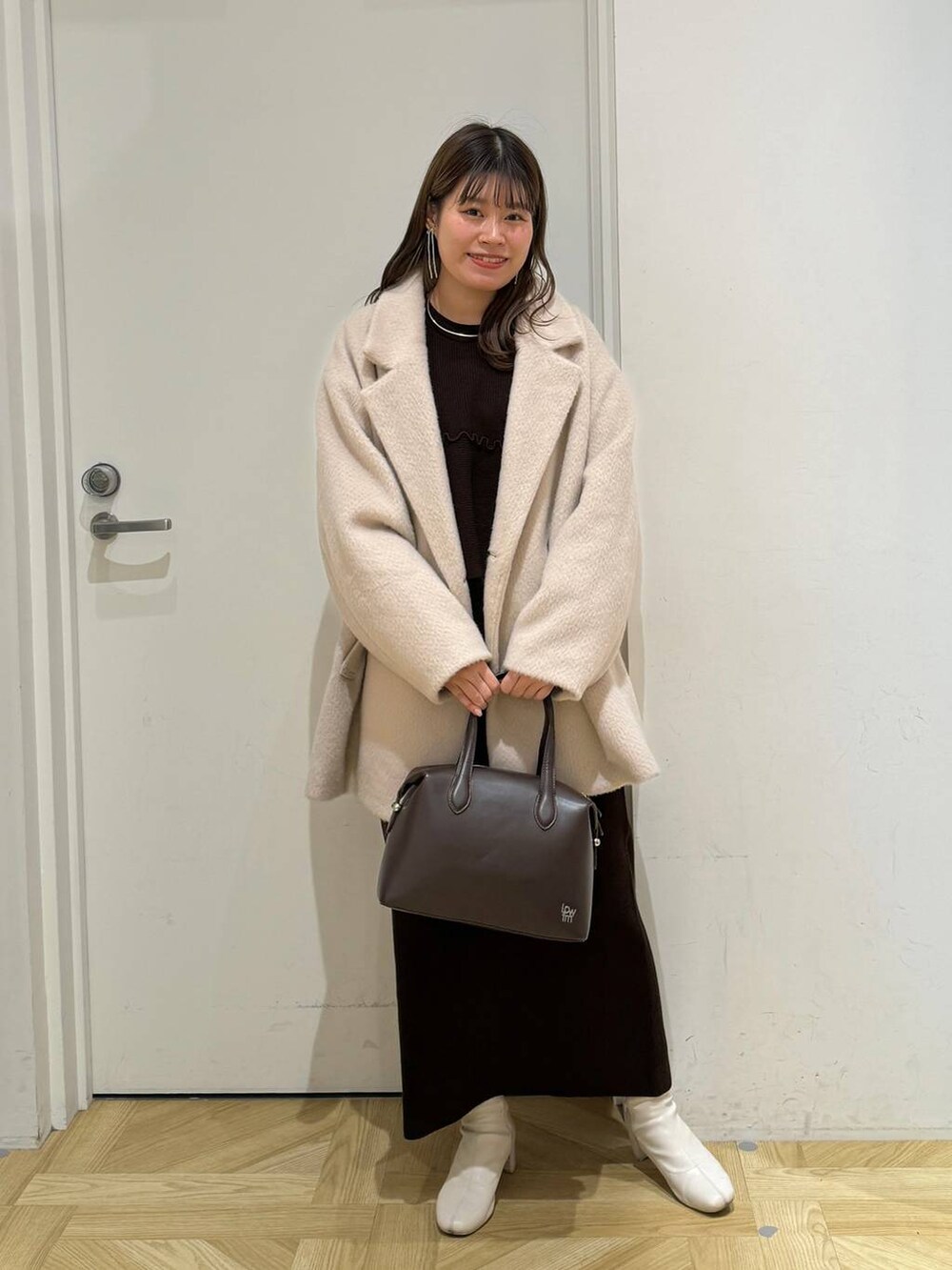 ホワイト系のブーツ、ブラウン系のショルダーバッグ、ブラウン系のワンピースを着用したレディースの冬コーディネートの2枚目の写真