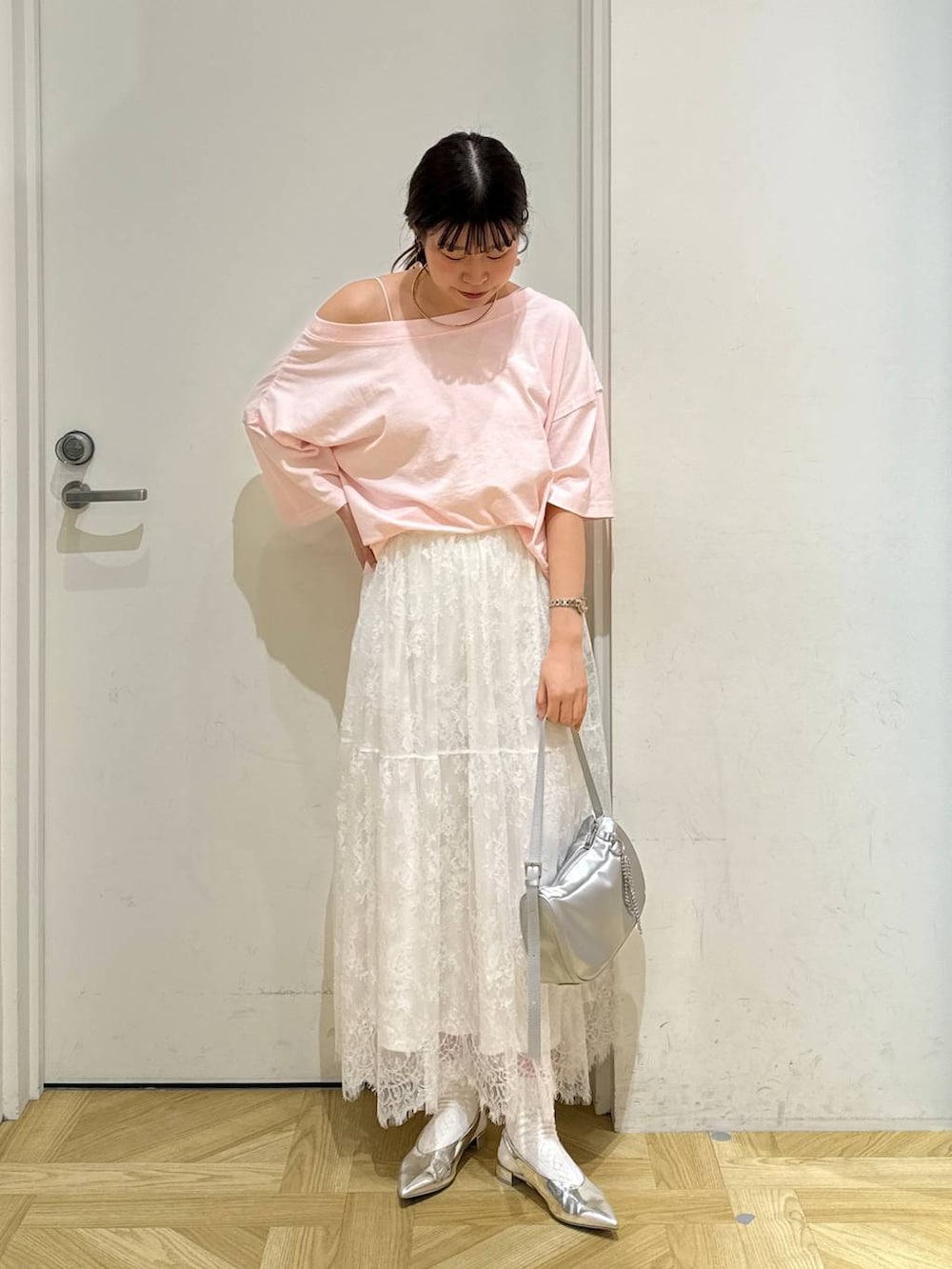 シルバー系のトートバッグ、シルバー系のパンプス、ホワイト系のスカートを着用したレディースの春コーディネートの3枚目の写真