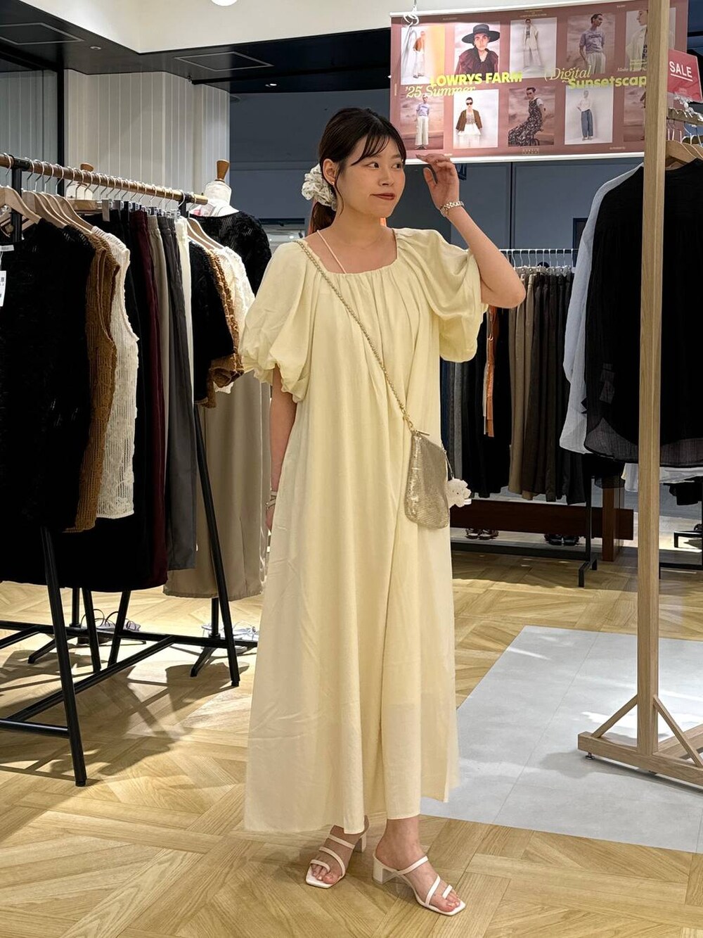 ゴールド系のショルダーバッグ、ホワイト系のサンダル、ホワイト系のワンピースを着用したレディースの夏コーディネートの4枚目の写真