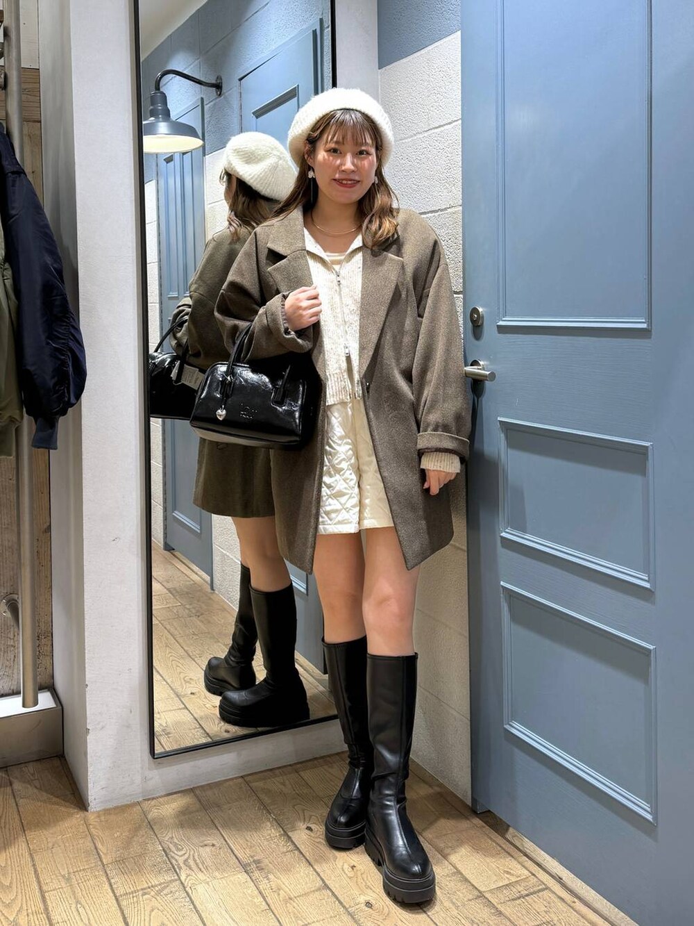 ブラウン系のチェスターコート、ホワイト系のその他パンツ、ブラック系のブーツを着用したレディースの秋コーディネートの2枚目の写真