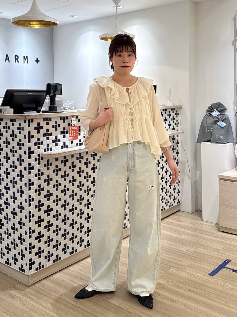 ブラック系のパンプス、ブルー系のデニムパンツ、ベージュ系のショルダーバッグを着用したレディースの春コーディネートの4枚目の写真