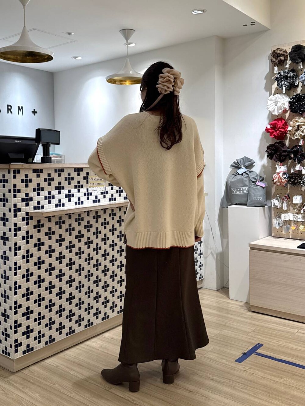 ホワイト系のニット/セーター、ブラウン系のスカート、ブラウン系のブーツを着用したレディースの冬コーディネートの4枚目の写真