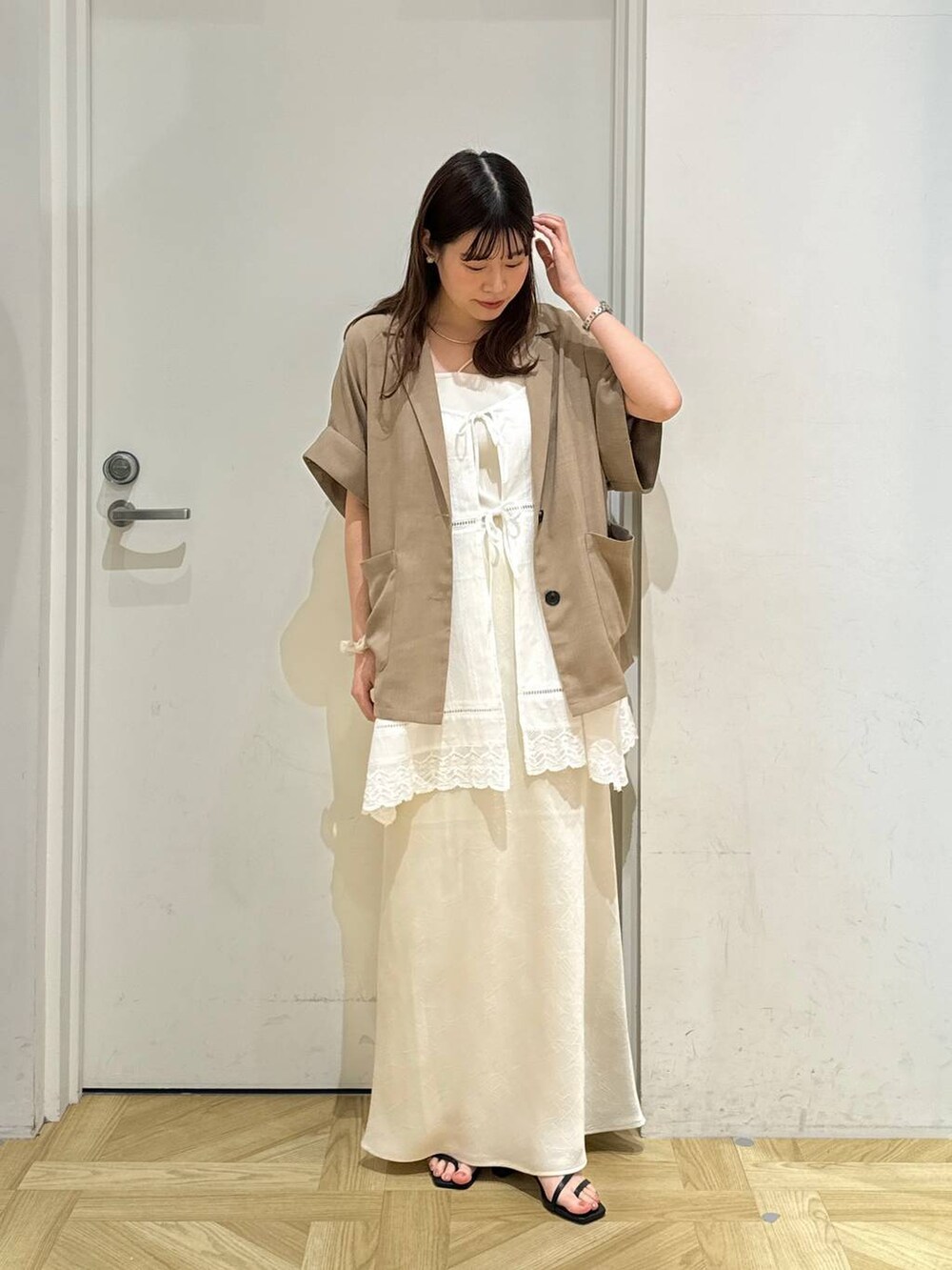 ホワイト系のスカート、ホワイト系のキャミソール、ブラック系のサンダルを着用したレディースの春コーディネートの2枚目の写真