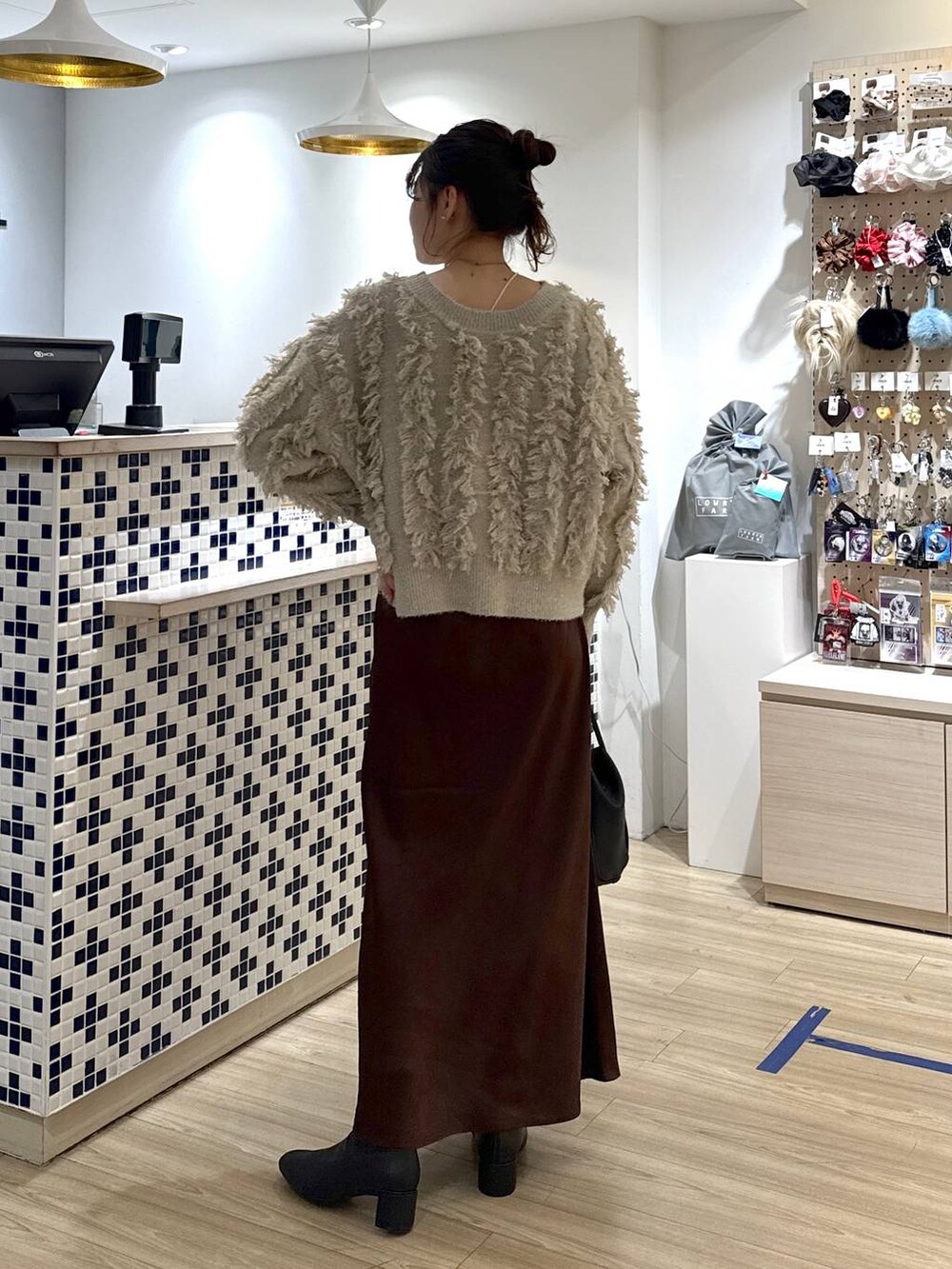 ブラウン系のスカート、ブラック系のショルダーバッグ、ベージュ系のカーディガン/ボレロを着用したレディースの冬コーディネートの5枚目の写真