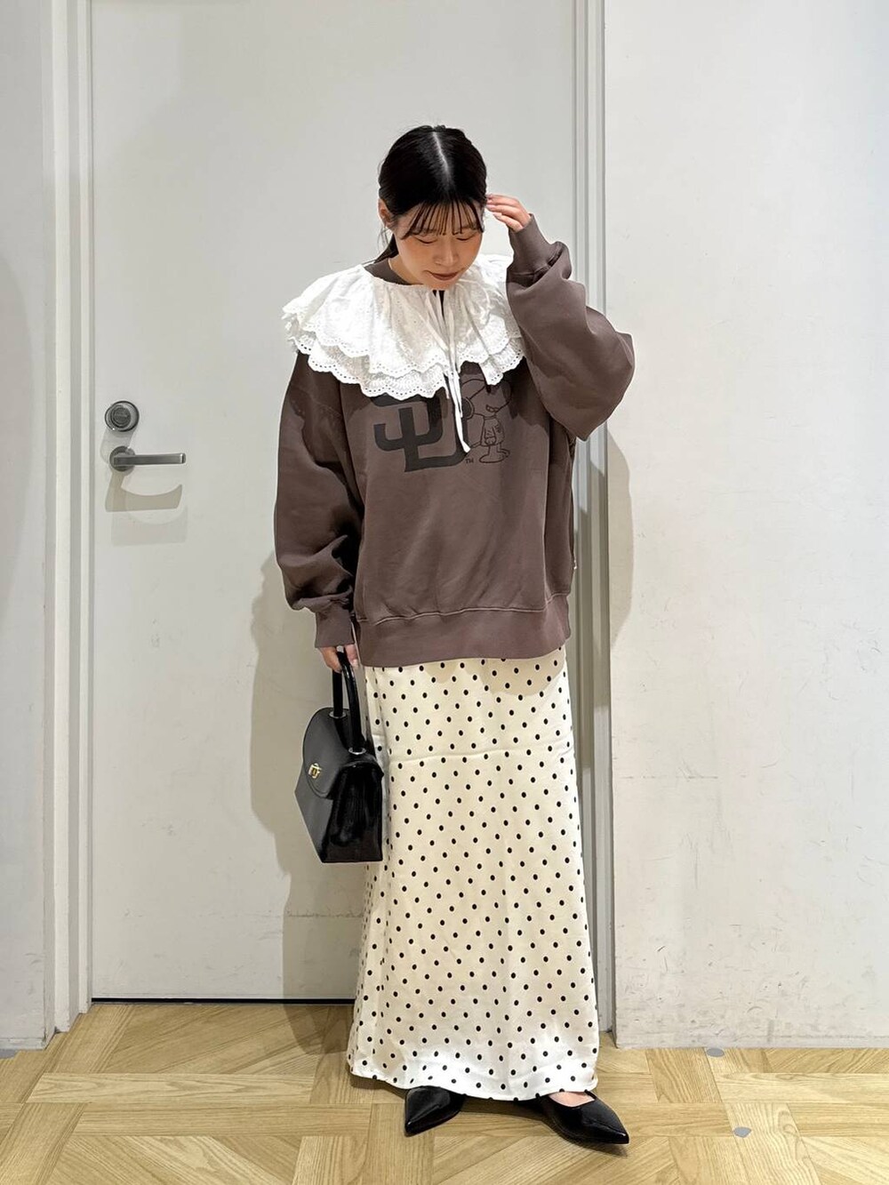 ホワイト系のスカート、ブラック系のボストンバッグ、ブラック系のパンプスを着用したレディースの秋コーディネートの2枚目の写真