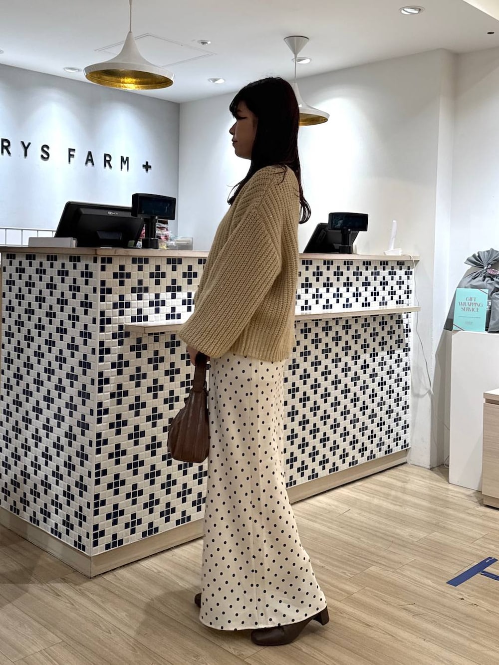 ホワイト系のスカート、ブラウン系のショルダーバッグ、ブラウン系のブーツを着用したレディースの冬コーディネートの3枚目の写真